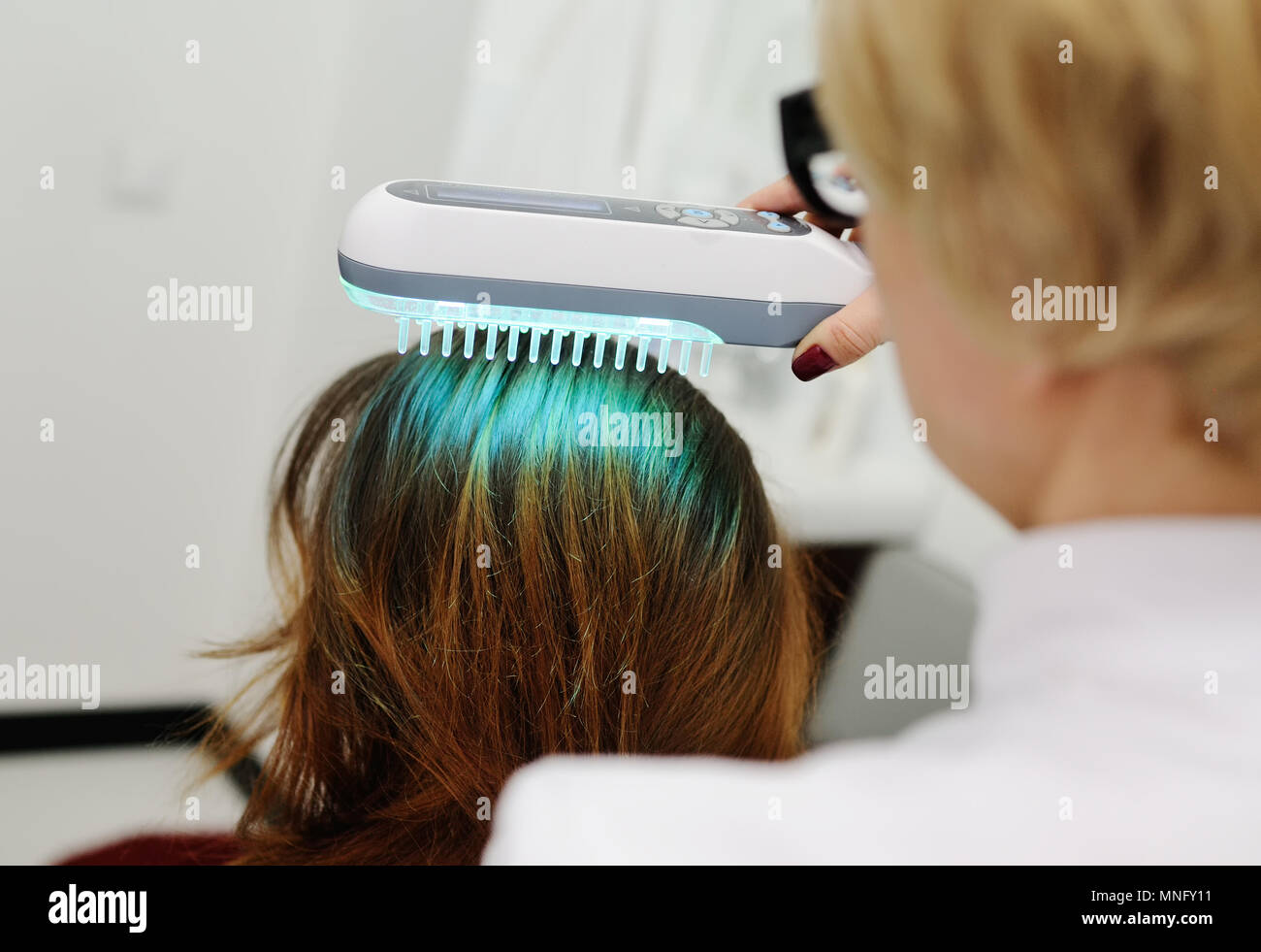 Doctor examines scalp a special device with a UV lamp Stock Photo