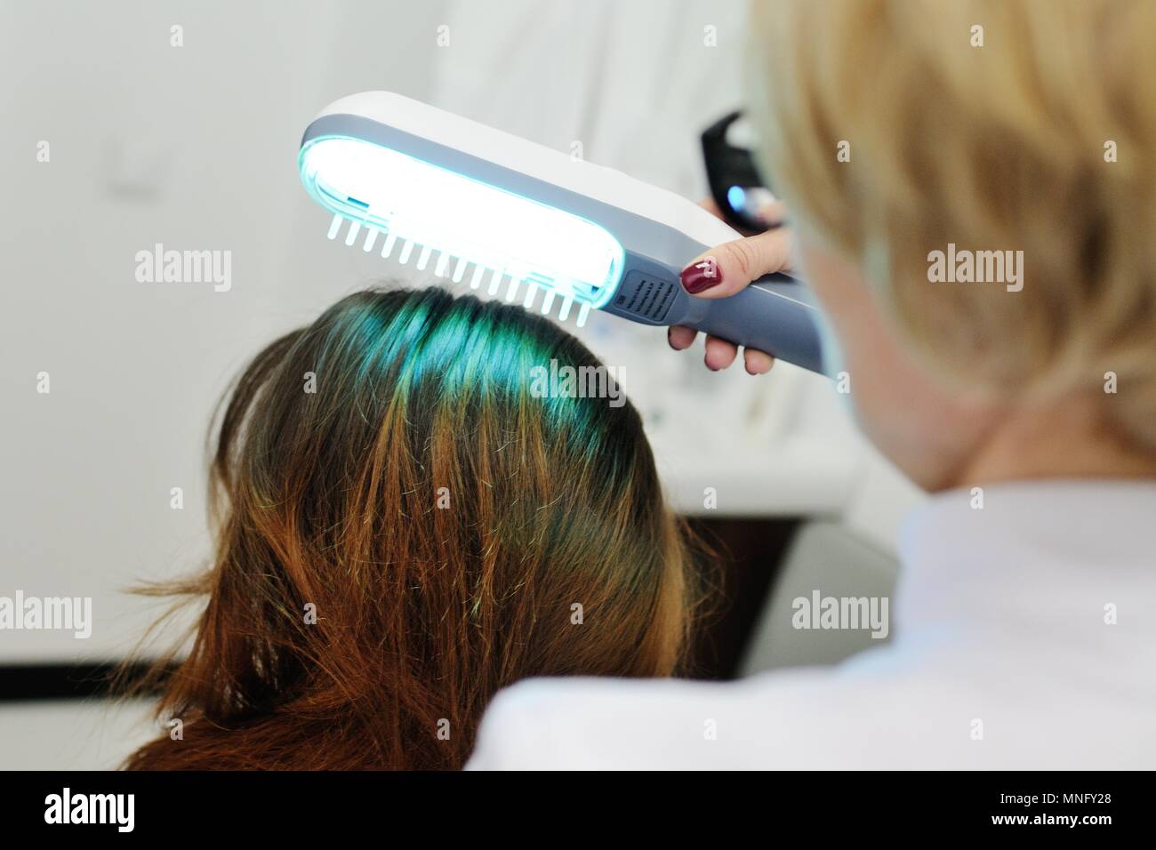 Doctor examines scalp a special device with a UV lamp Stock Photo