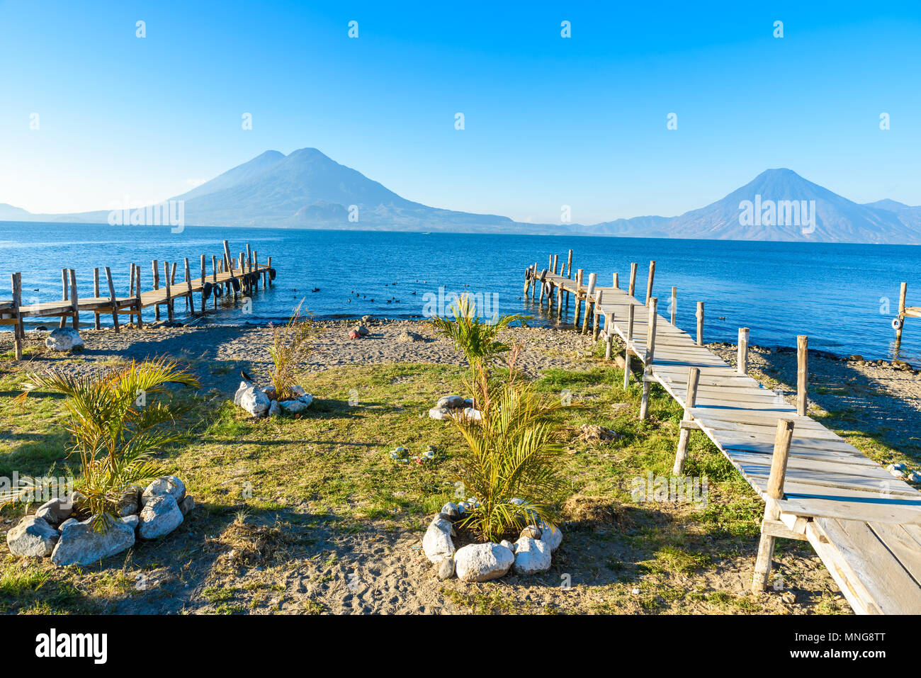 Wooden pier at Lake Atitlan on the beach in Panajachel, Guatemala.  With beautiful landscape scenery of volcanoes Toliman, Atitlan and San Pedro in th Stock Photo