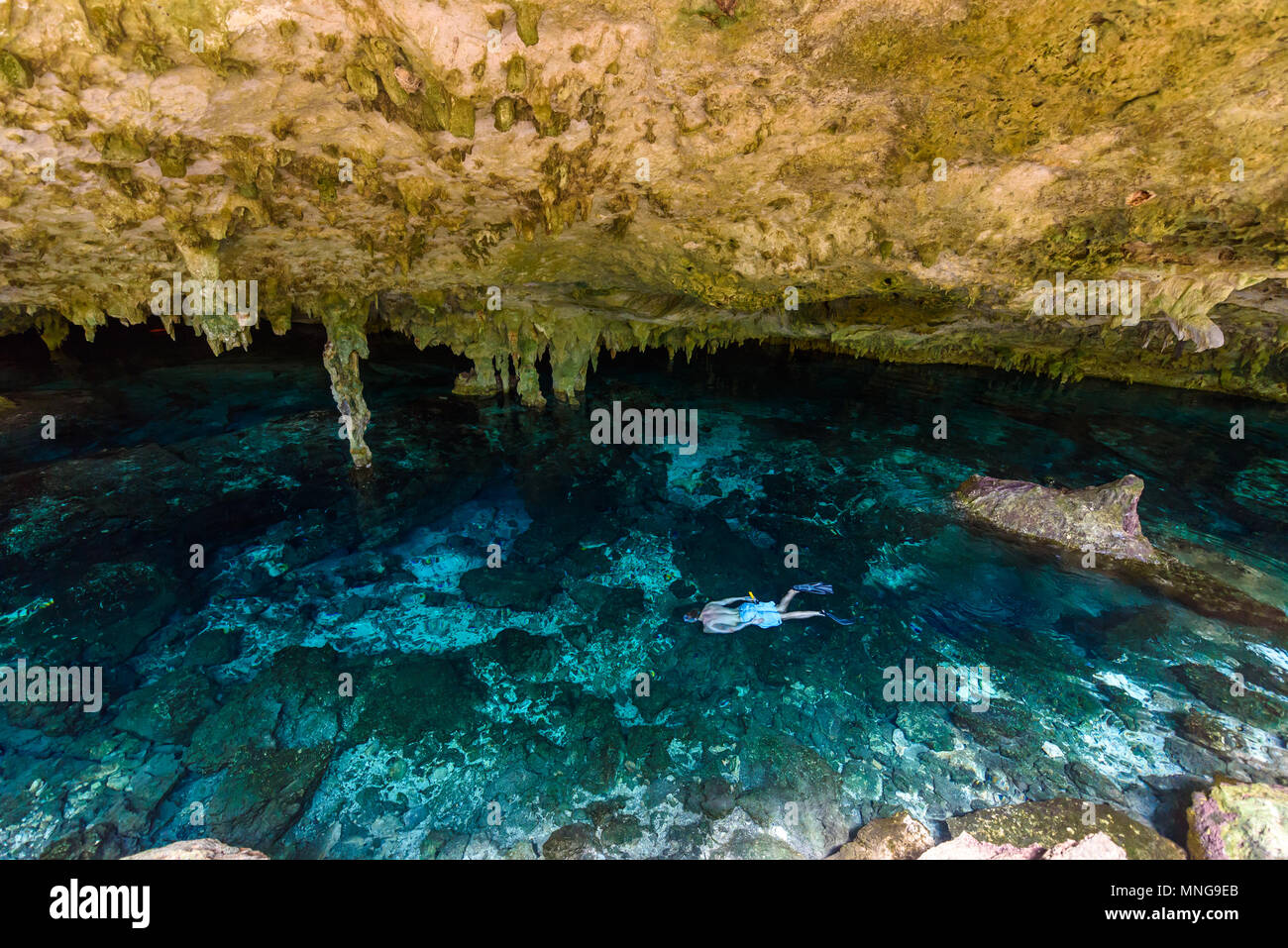 Cenote Dos Ojos in Quintana Roo, Mexico. People swimming and snorkeling in clear water. This