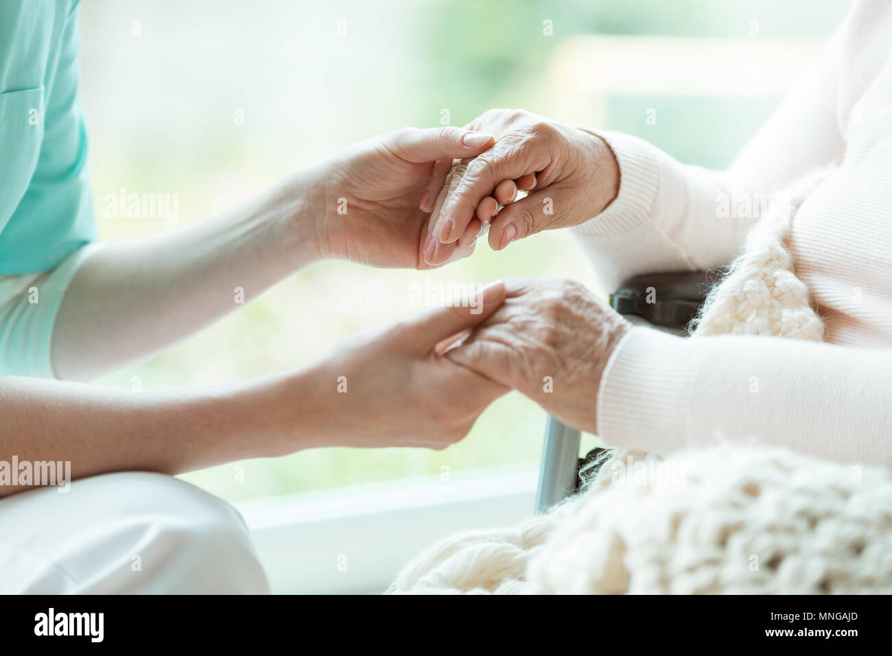 Photo of nurse holding her woman patient's hands with painted nails