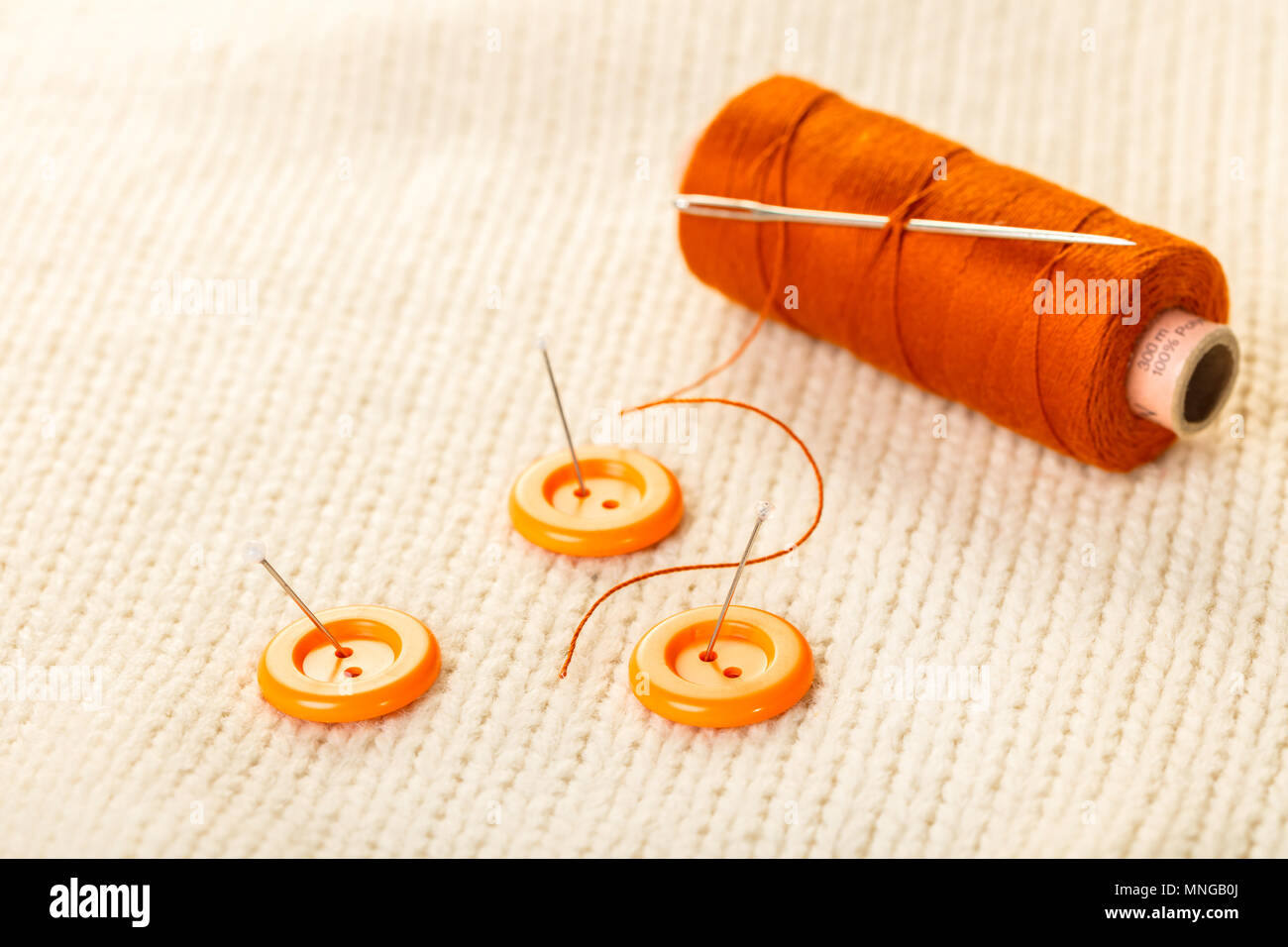 colored thread and buttons on white knitted fabric Stock Photo - Alamy
