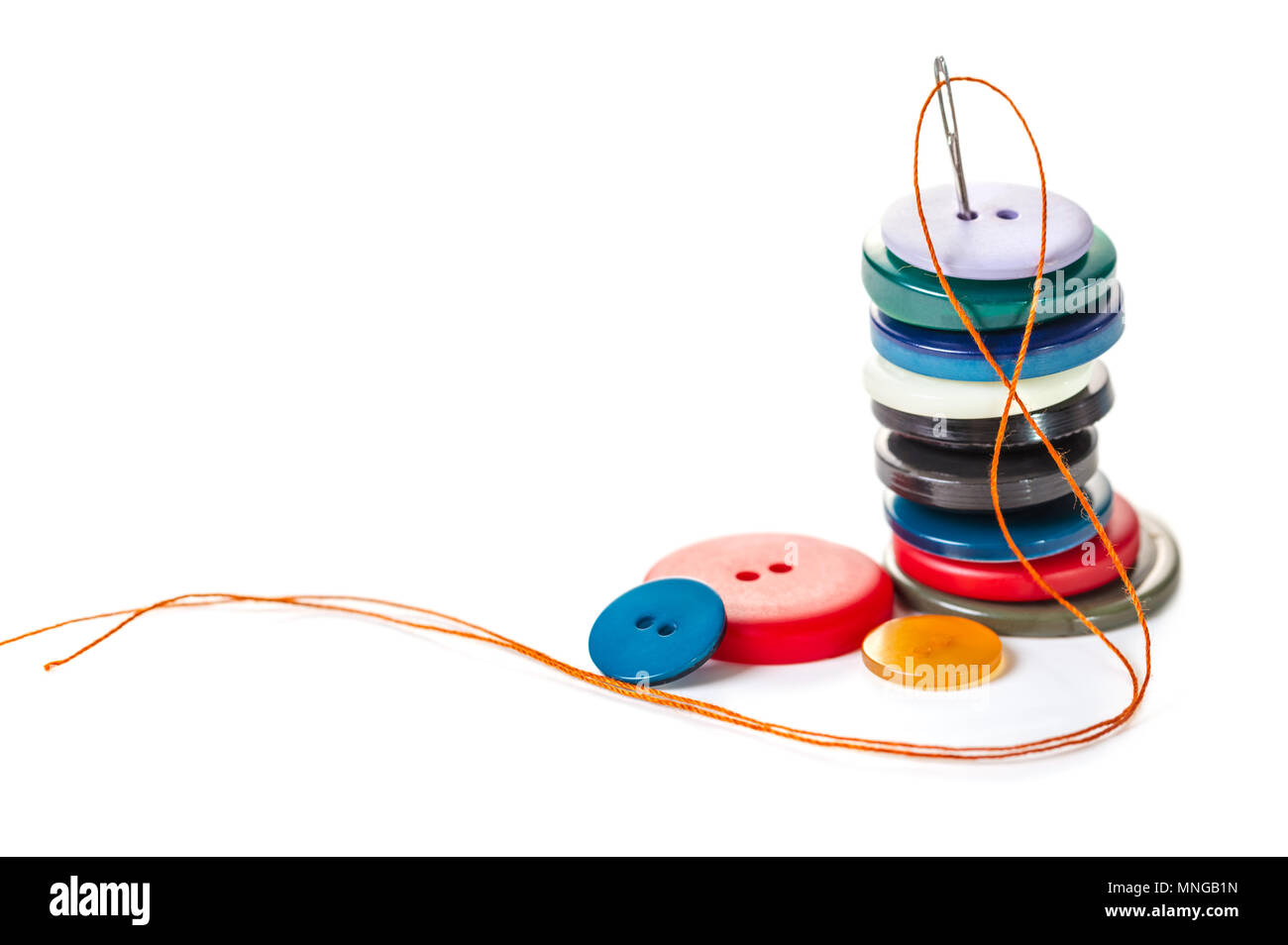 Needle with orange thread and buttons on a white isolated background Stock Photo