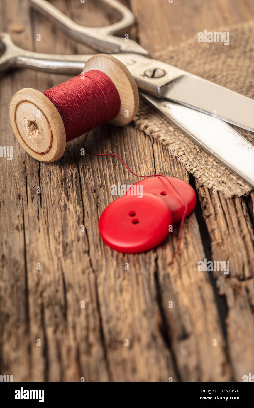 red thread with buttons and scissors, wooden background Stock Photo
