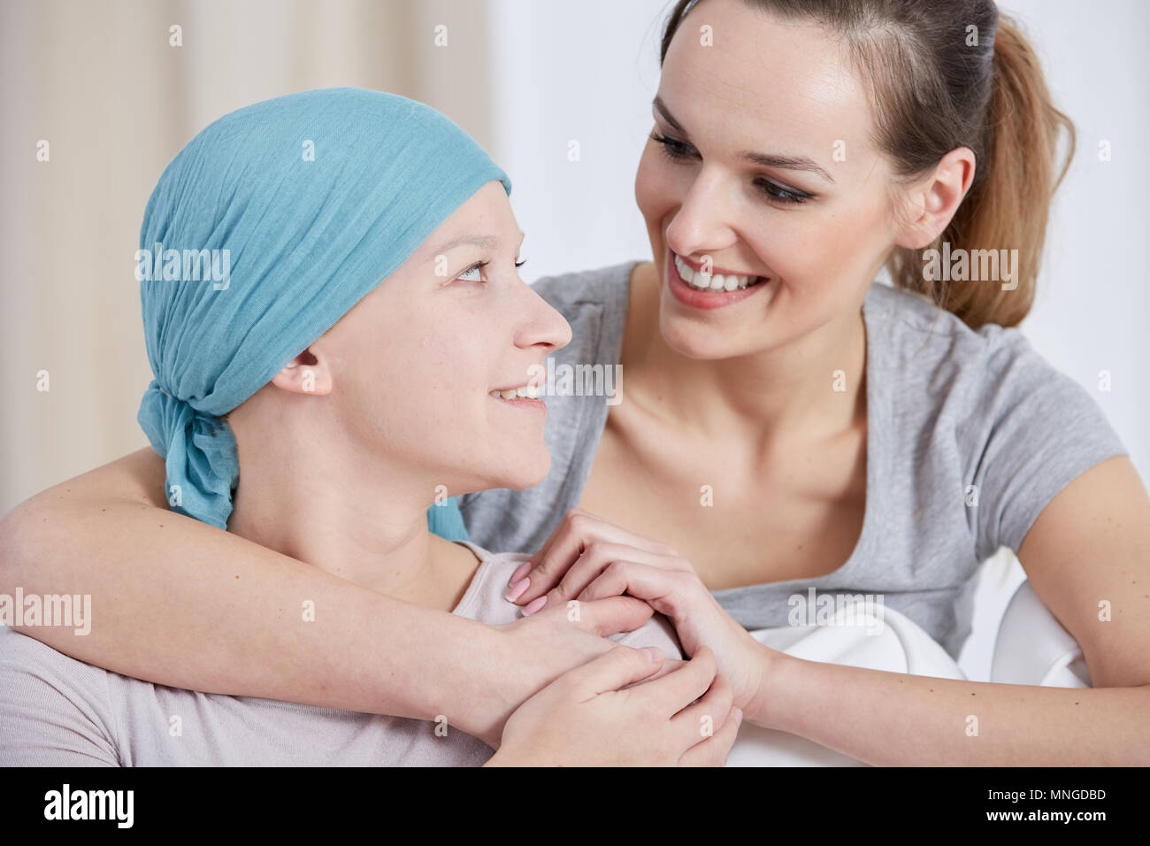 Hopeful cancer woman wearing headscarf, talking with friend Stock Photo