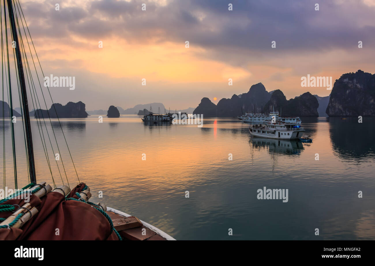 A beautiful sunrise among the limestone islets and cruise ships in Ha Long Bay, a UNESCO World Heritage Site, in Quang Ninh Province, Vietnam. Stock Photo