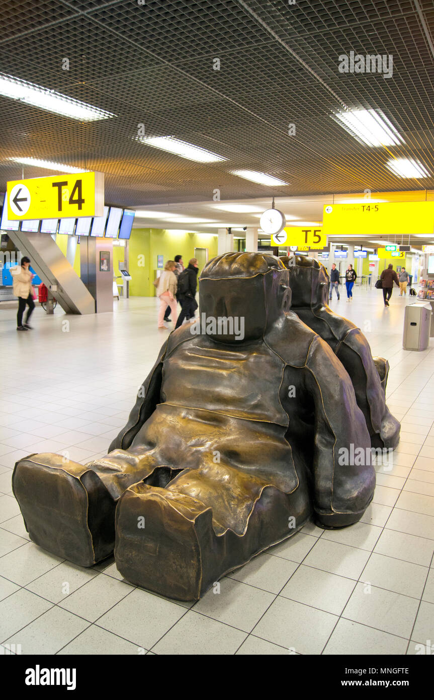 Metal sculpture of two people sitting back to back in the departure lounge at Schiphol International Airport in Amsterdam, The Netherlands. Stock Photo