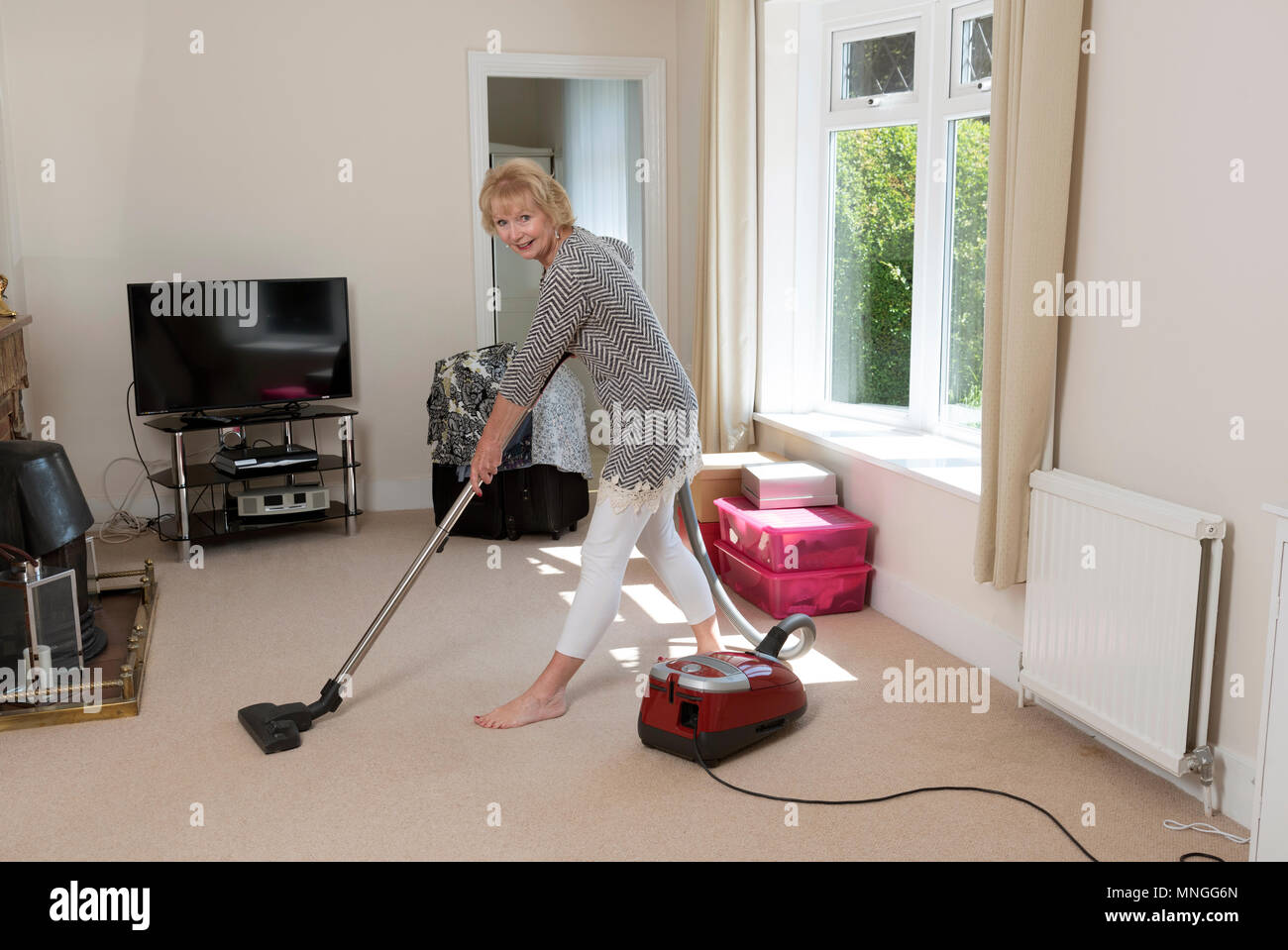Moving home, Woman using a vacum cleaner to hoover the carpet before