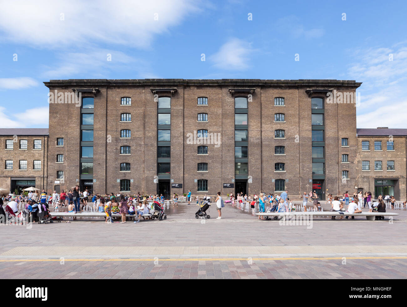 People playing in the water fountain outside the redeveloped Granary Building in King's Cross. Stock Photo