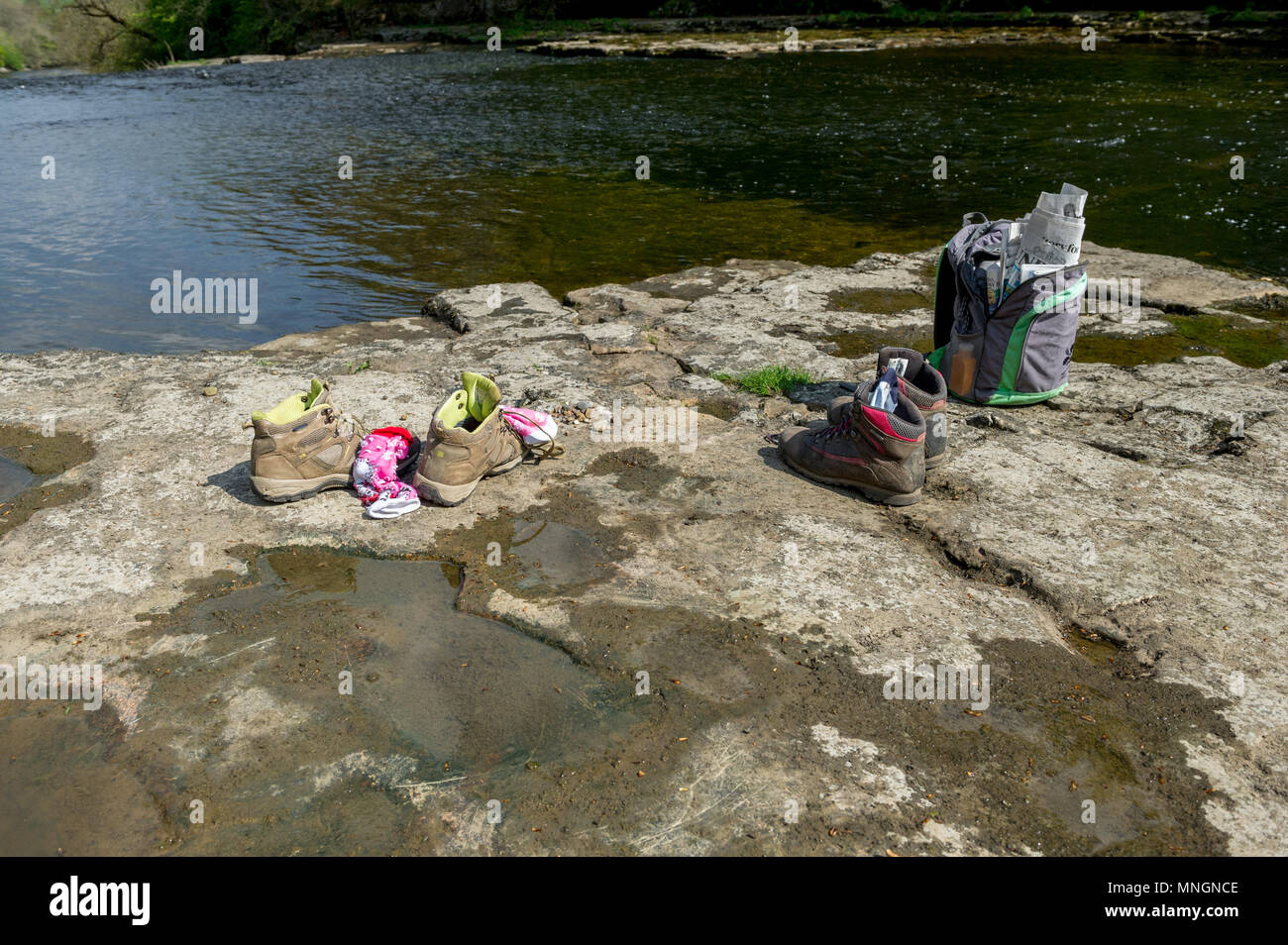 Walking booths and socks at the side of a river. Stock Photo