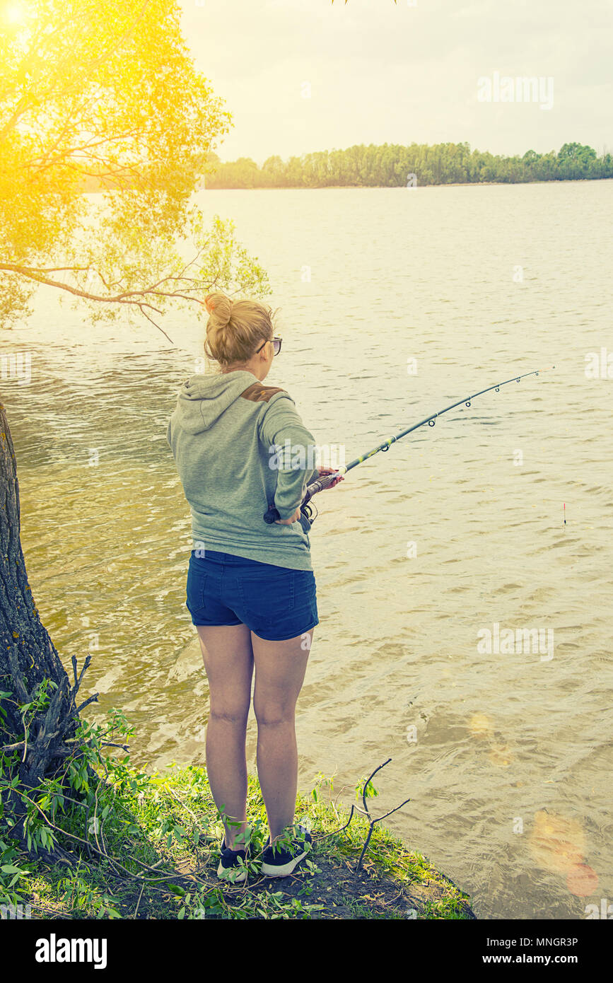 https://c8.alamy.com/comp/MNGR3P/girl-with-a-fishing-rod-fishing-in-the-pond-on-a-sunny-lake-MNGR3P.jpg