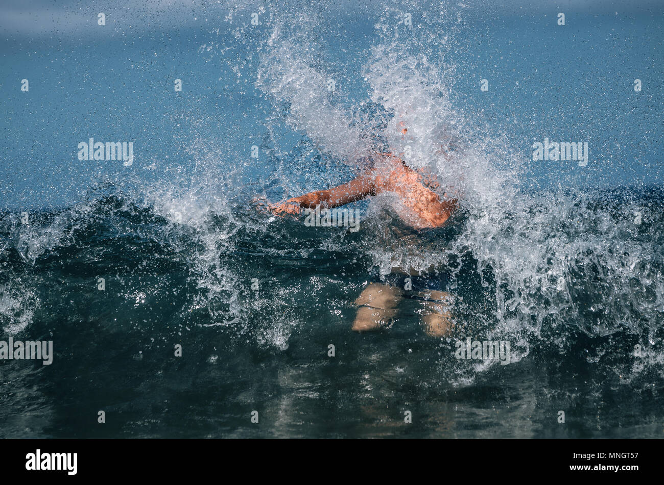 Man covered by waves of ocean with splashes Stock Photo