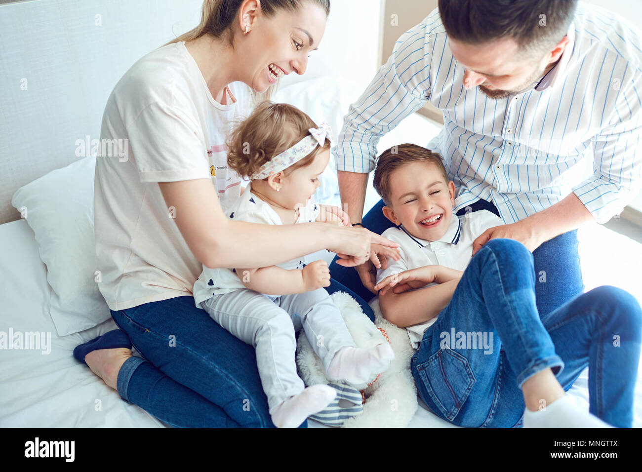 Happy family playing lying on the bed in the bedroom. Stock Photo