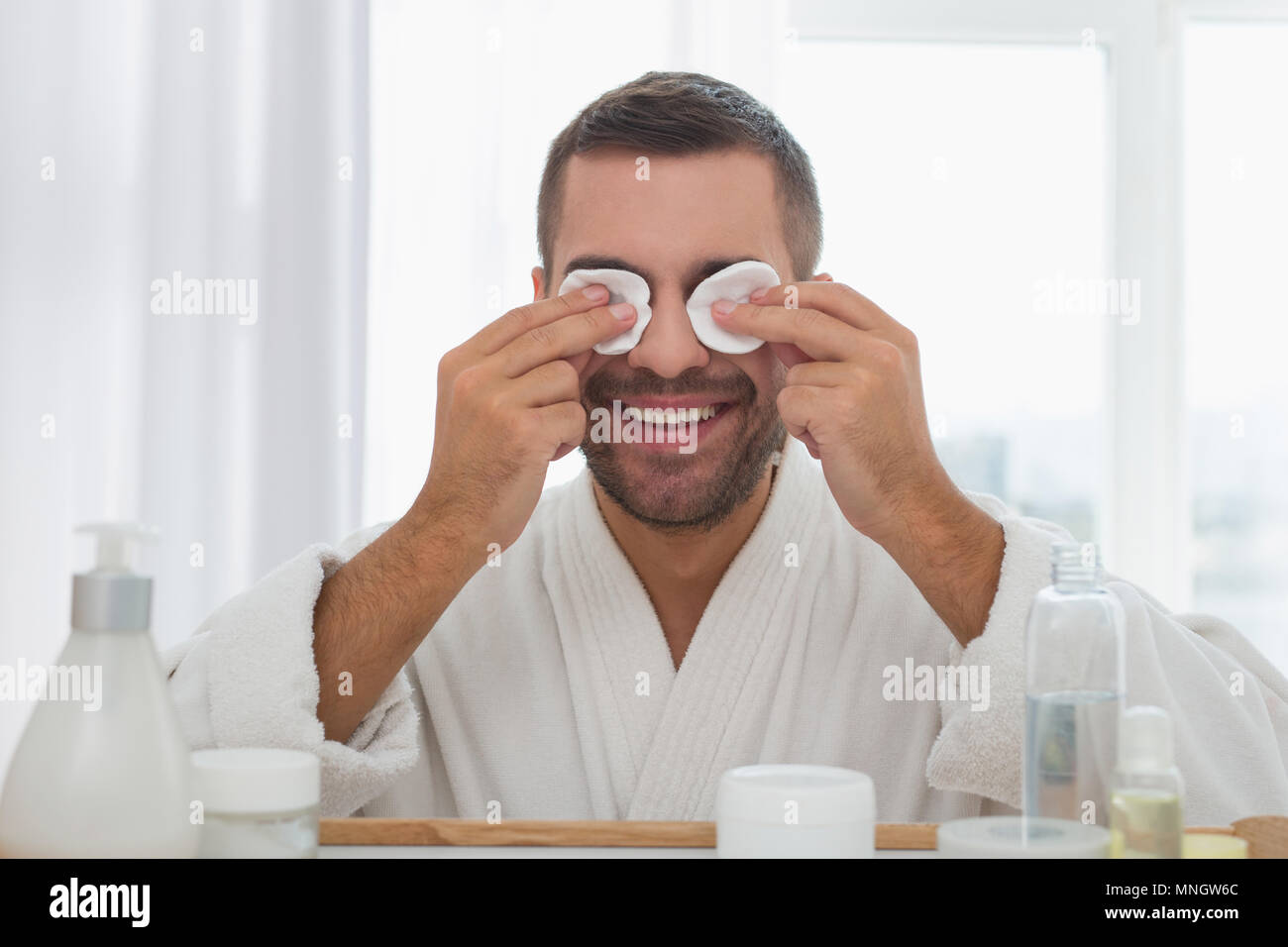 Positive handsome man putting cotton pads on his eyes Stock Photo Alamy