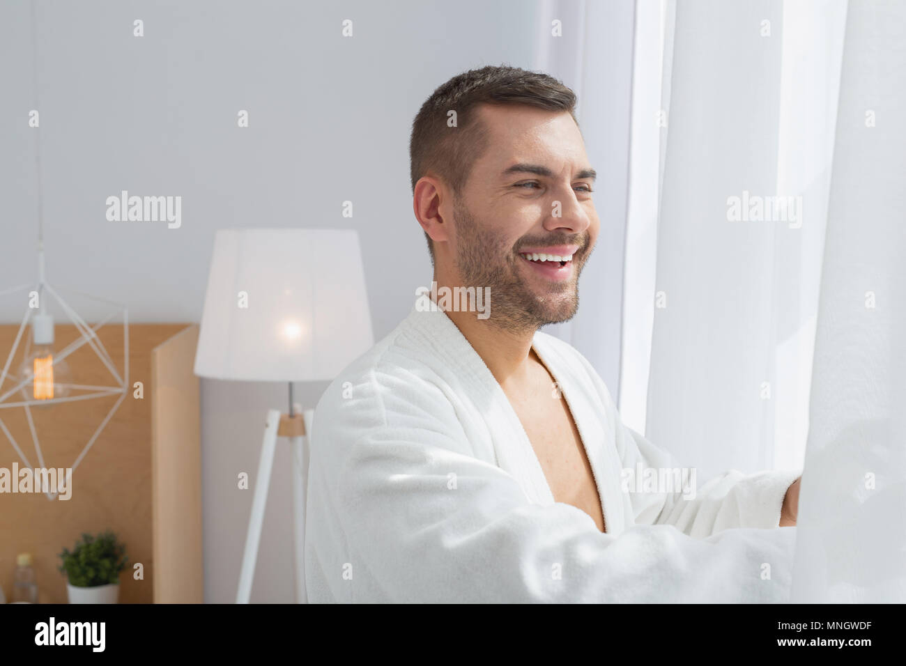 Nice joyful man looking outside the window Stock Photo