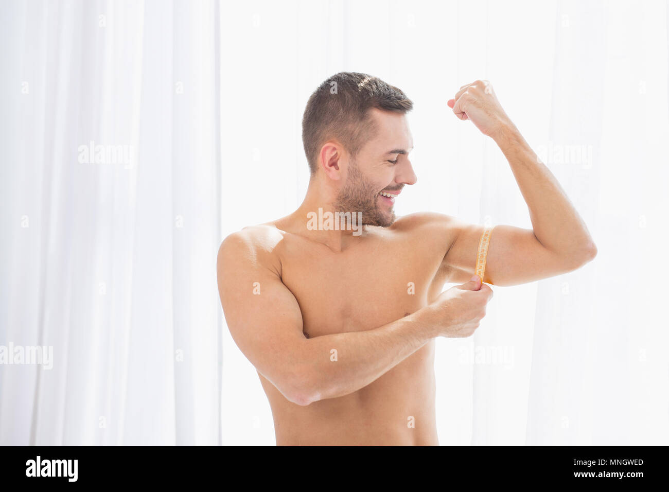 Nice handsome sportsman looking at his muscles Stock Photo