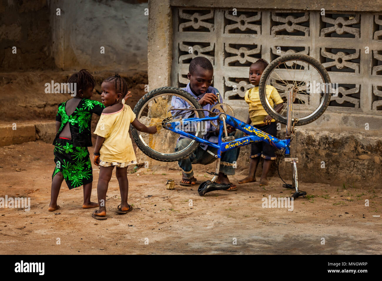 Yongoro, Sierra Leone - June 03, 2013: West Africa, unknown man with children repairs a bicycle in the village in front of the capital Freetown, SIerr Stock Photo