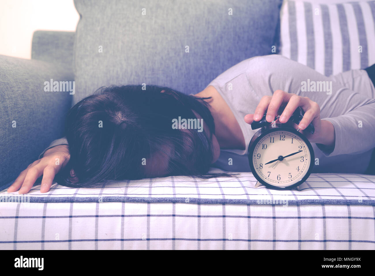 Lazy women are laying down on the sofa after the clock alarm, late wakeup lifestyle concept Stock Photo