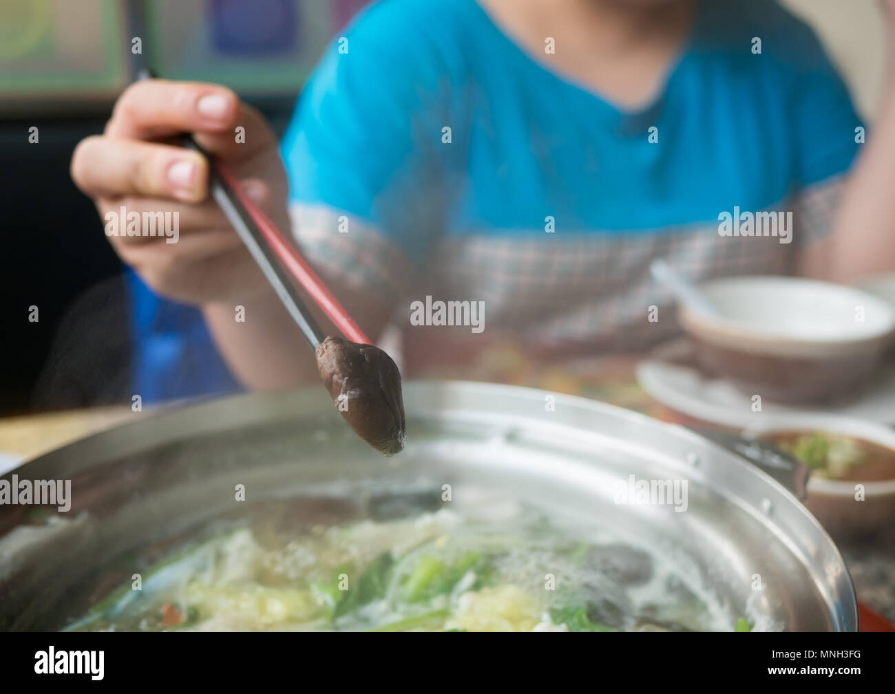 Blurred image muchroom in chopsticks on hand woman, Stock Photo