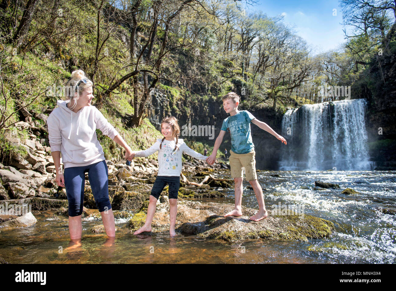 The Four Waterfalls Walk near Pontneddfechan in the Brecon Beacons - a family paddles at the Sgwd yr Eira falls (Falls of Snow) on the River Hepste Stock Photo