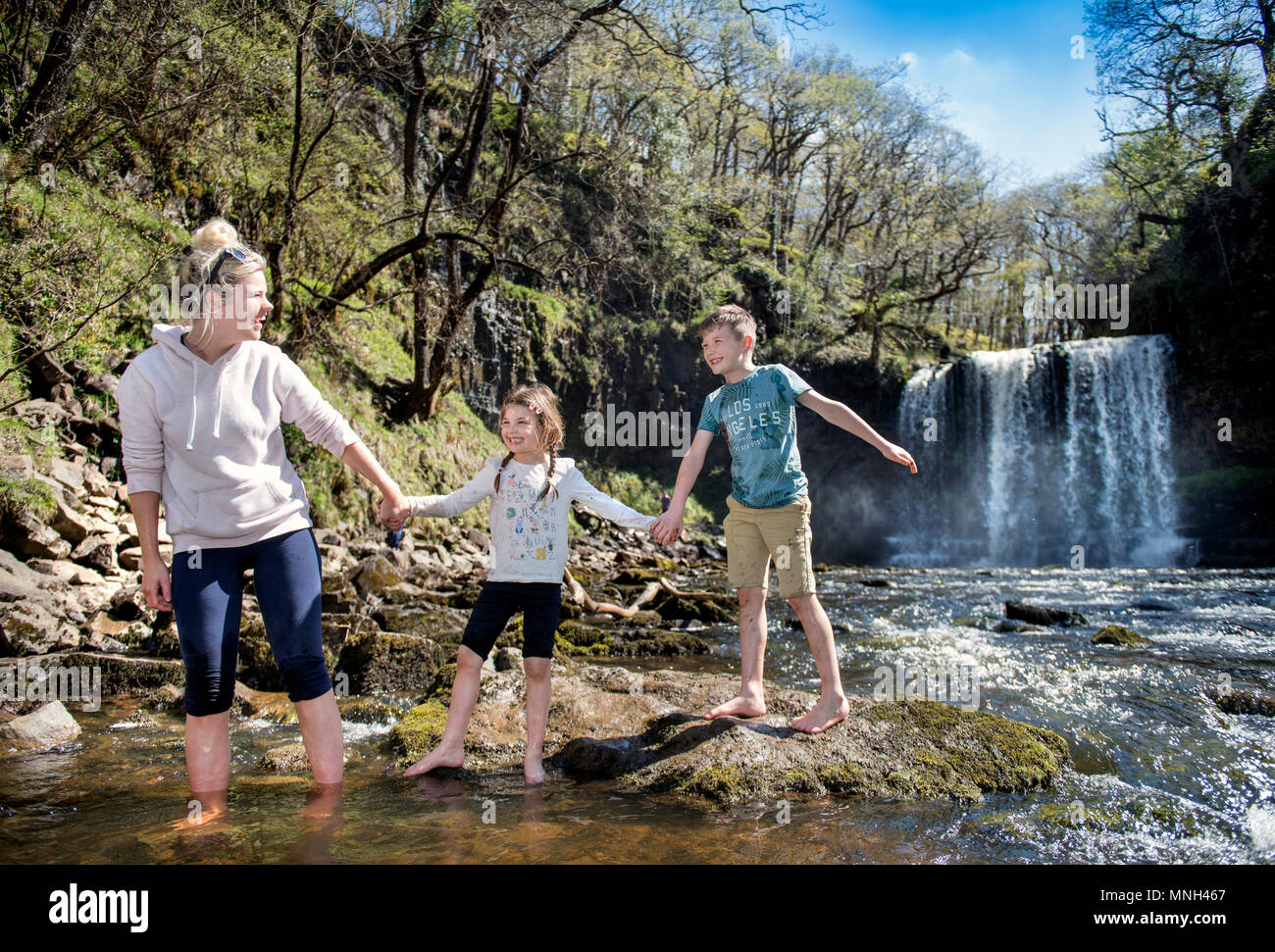The Four Waterfalls Walk near Pontneddfechan in the Brecon Beacons - a family paddles at the Sgwd yr Eira falls (Falls of Snow) on the River Hepste Stock Photo