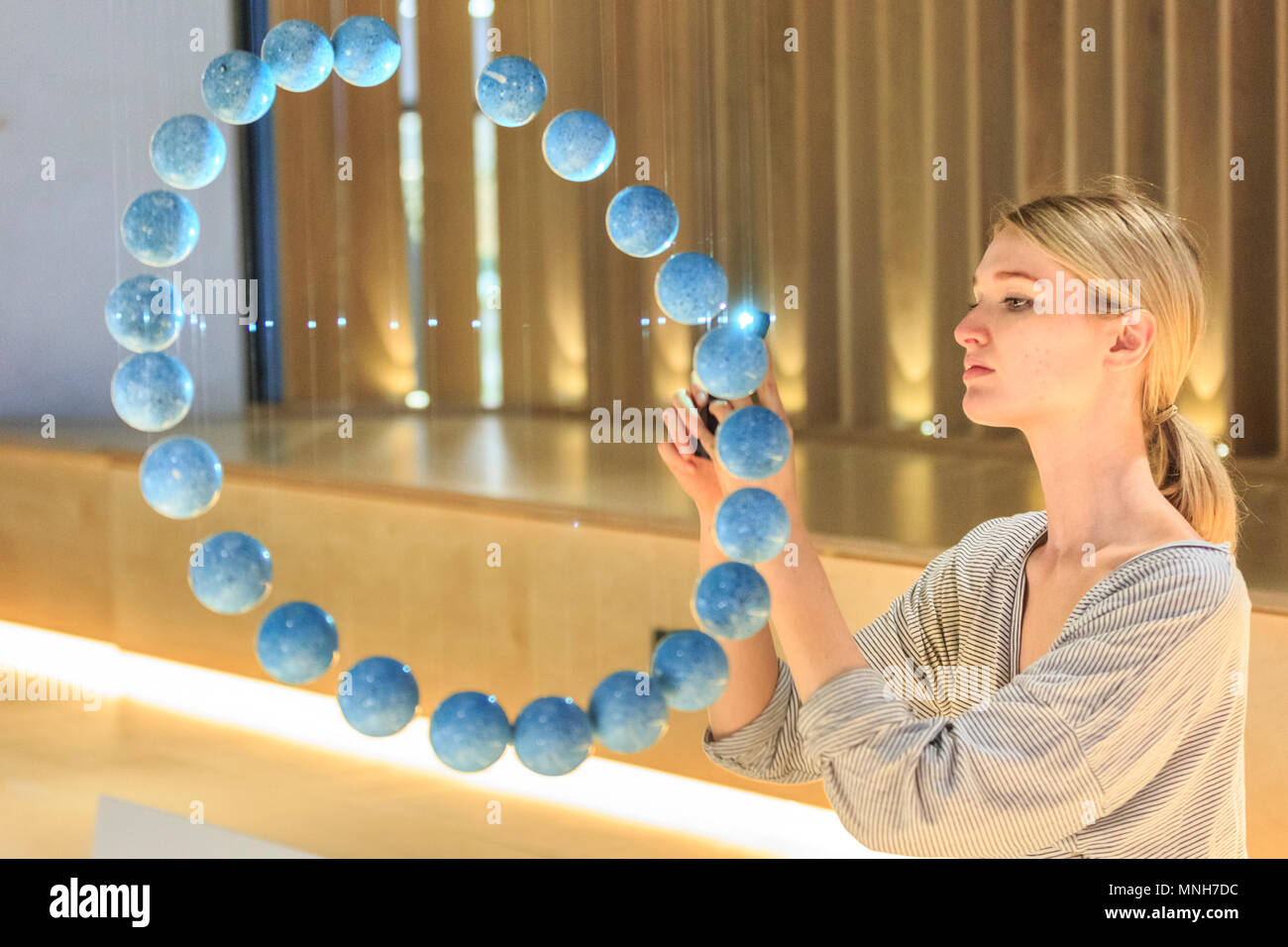 Westminster, London, 17th May 2018.  An assistant looks at “Floating flødeboller”, the cake special Royal Wedding Cake by designer and cake maker Kia Utzon-Frank, who created her own special suspended Royal Wedding Cake, made of 24 chocolate spheres hanging in a ring formation. In advance of Clerkenwell Design Week (22 – 24 May), some of London’s leading creatives, in partnership with top bakers, have been commissioned, to create their own dream wedding cake for Meghan and Harry to celebrate the Royal Wedding on the 19th May. Credit: Imageplotter News and Sports/Alamy Live News Stock Photo