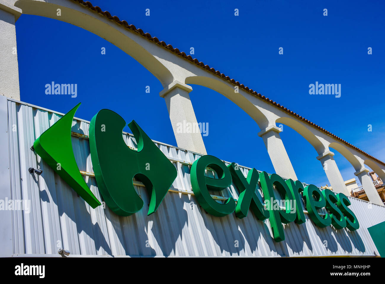 Express, the small local brand of Carrefour. Carrefour Express brand logo in Guardamar del Segura, Spain. Blue sky. French multinational Stock Photo