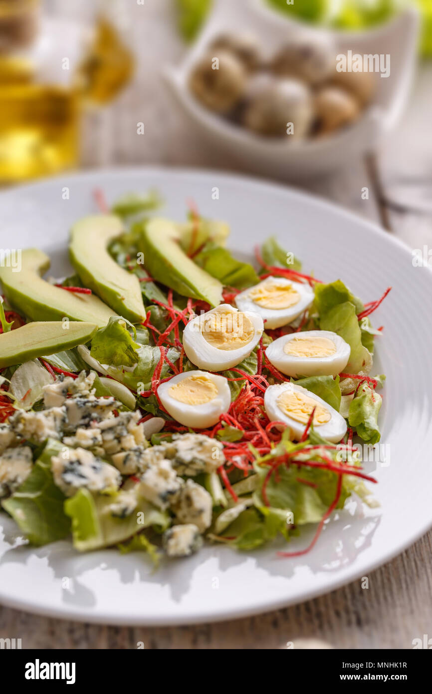 Close up of fresh salad with avocado, quail egg and blue cheese Stock Photo