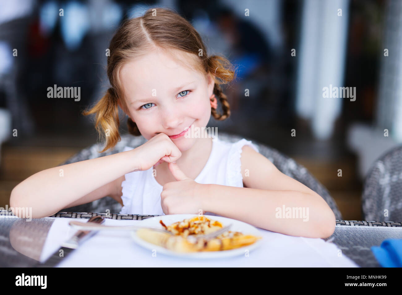 Adorable little girl eating breakfast in restaurant Stock Photo