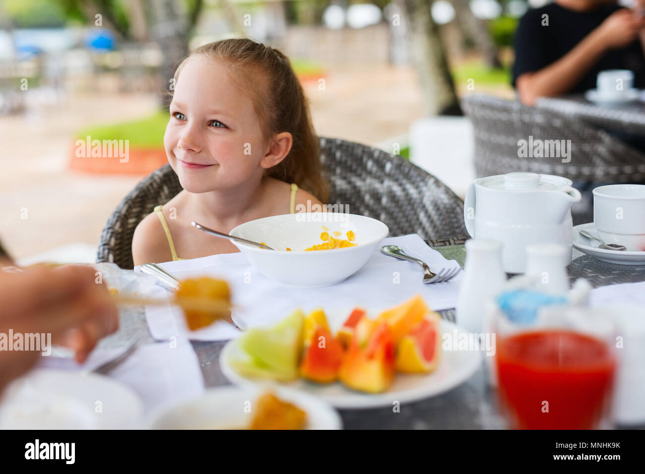 Adorable little girl eating cereal with milk for breakfast in restaurant Stock Photo