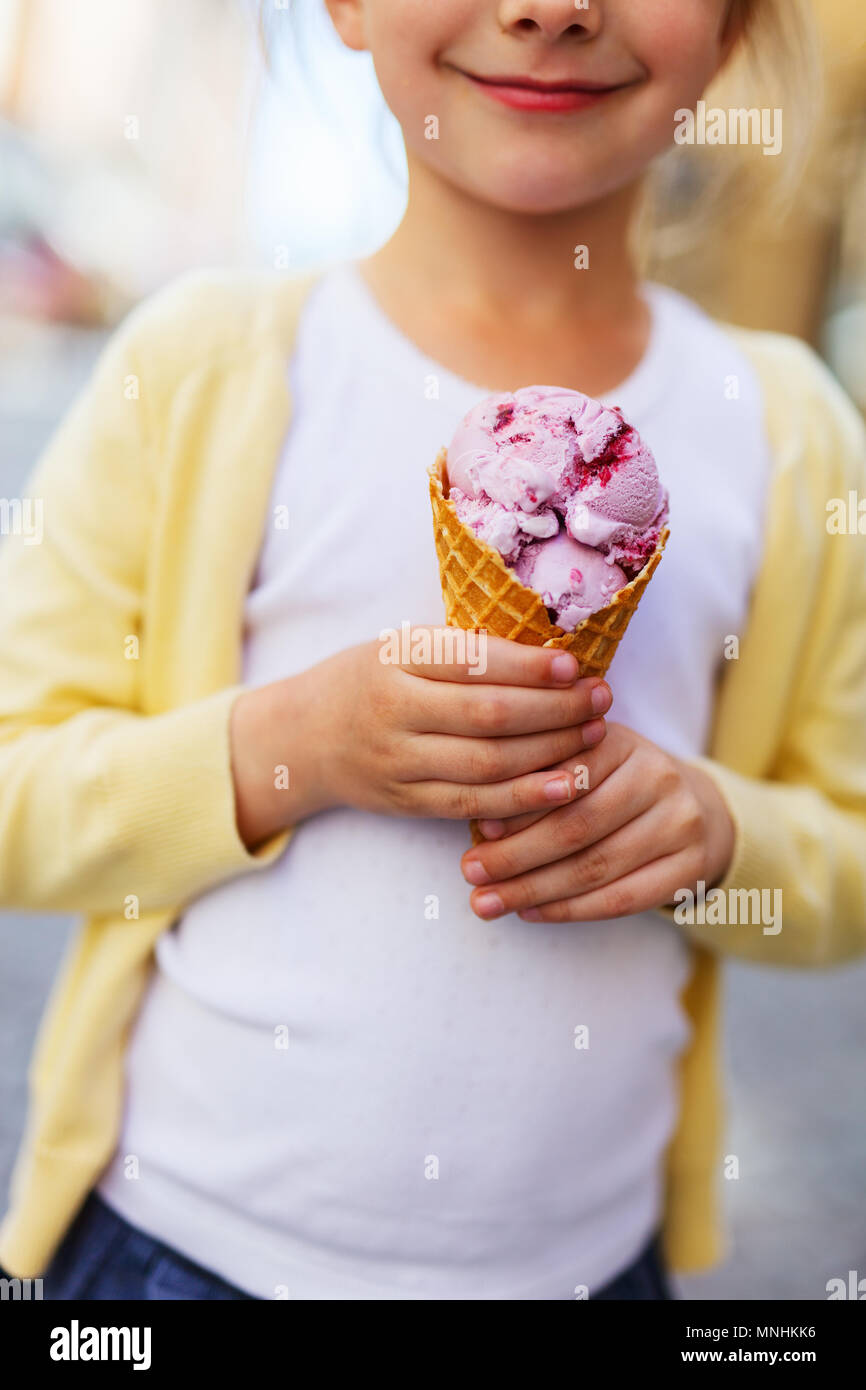 Adorable little girl eating ice cream in a fresh waffle cone outdoors on summer day Stock Photo
