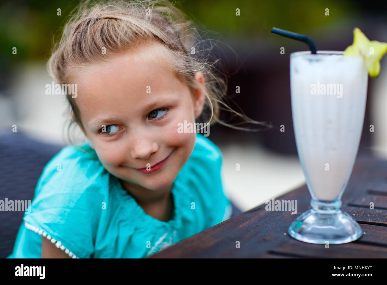 Adorable little girl drinking fresh smoothie at outdoor cafe on summer day Stock Photo