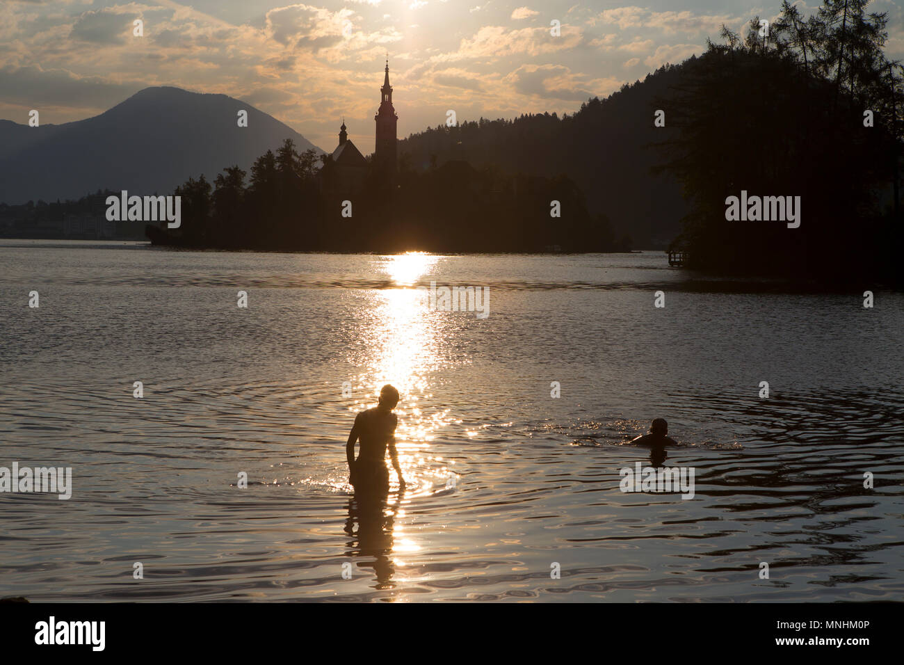 Silhouettes of two boys swimming in Lake Bled at sunset, Bled, Upper Carniola, Slovenia Stock Photo