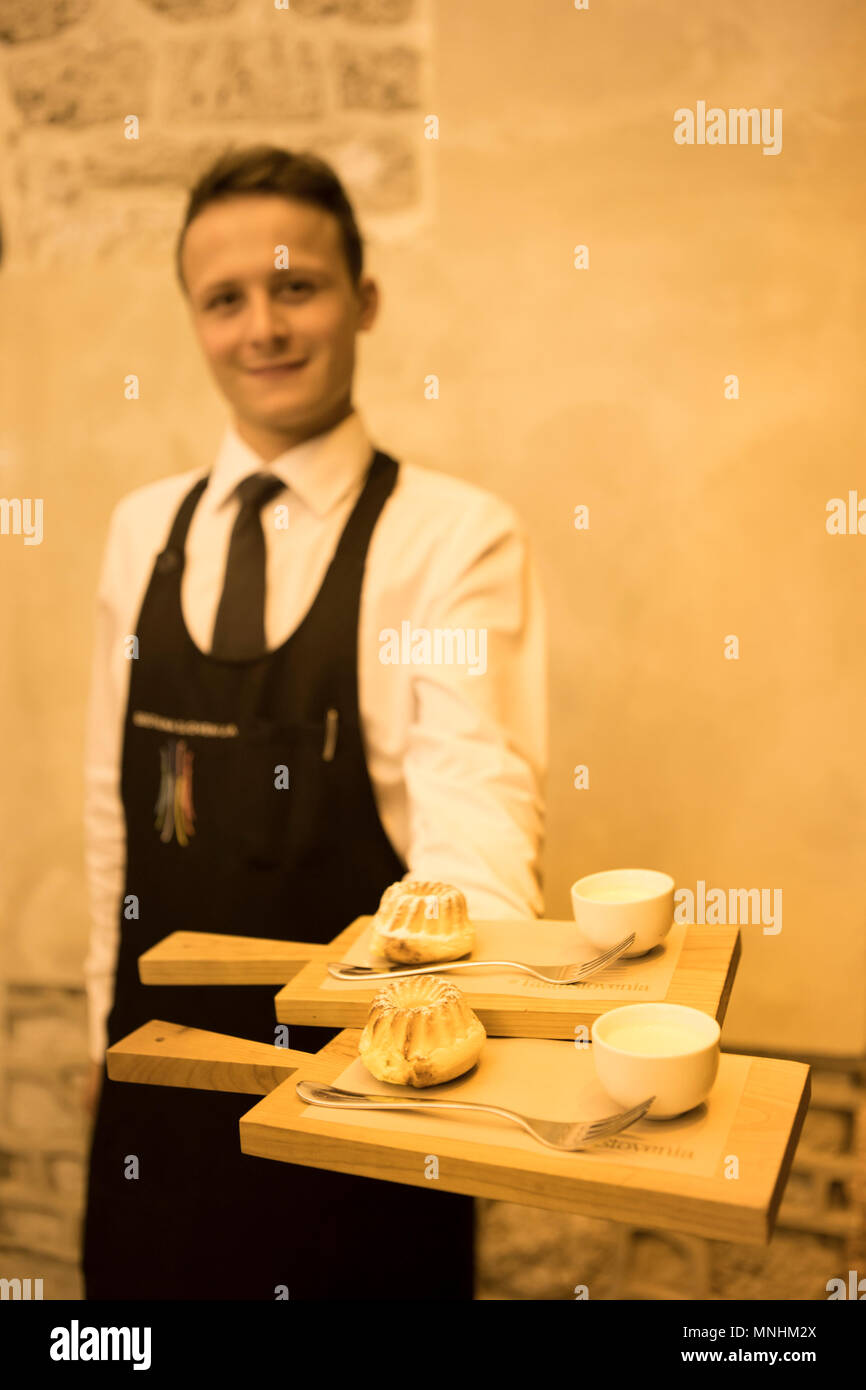 Waiter holding dessert plates in famous Bled castle restaurant, situated above Bled Lake in Slovenia Stock Photo