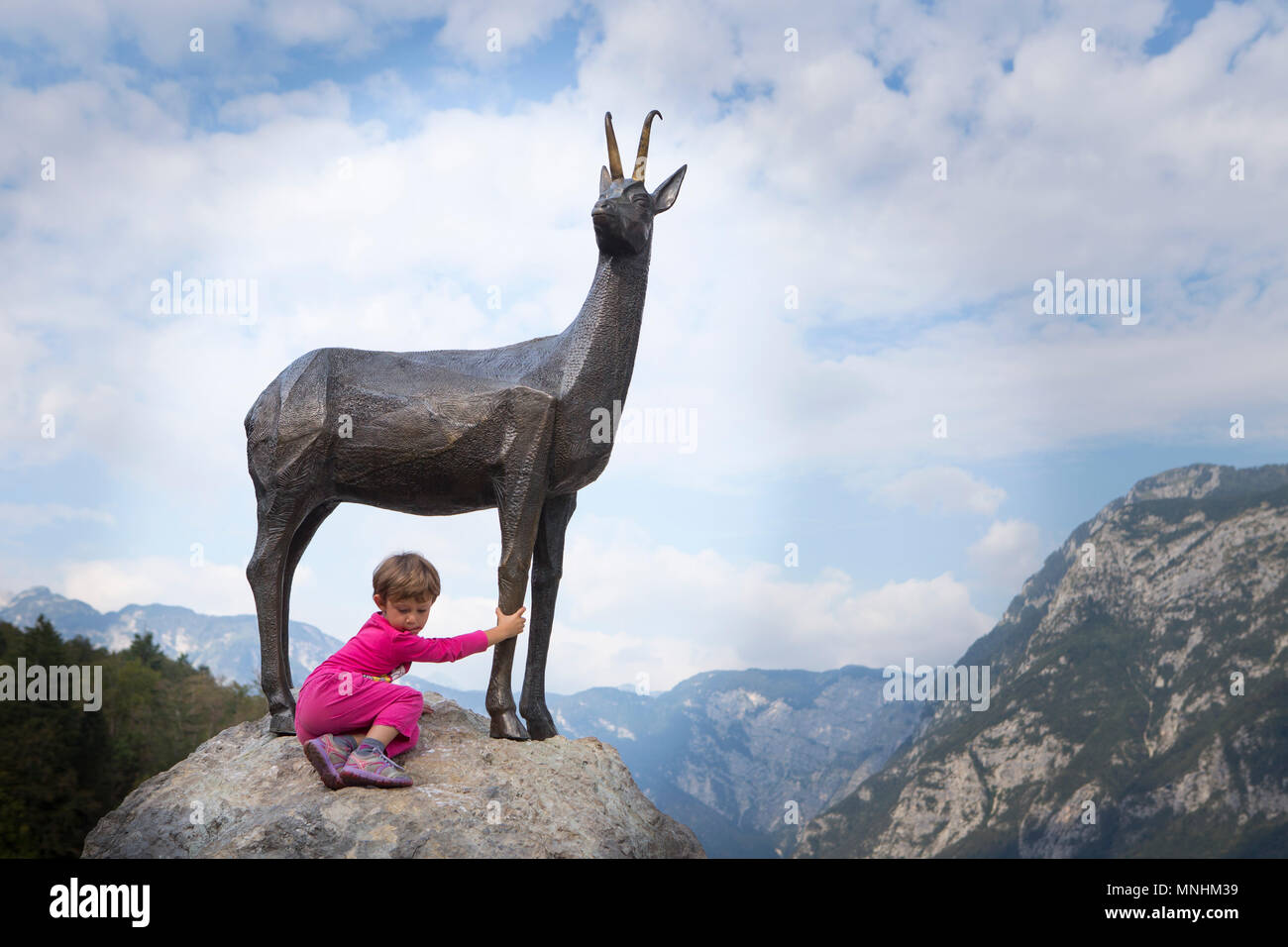 Girl at statue of Zlatorog, legendary white chamois buck, or in some Slovenian stories steinbock, who had his realm in heights of Mount Triglav, Slovenia Stock Photo