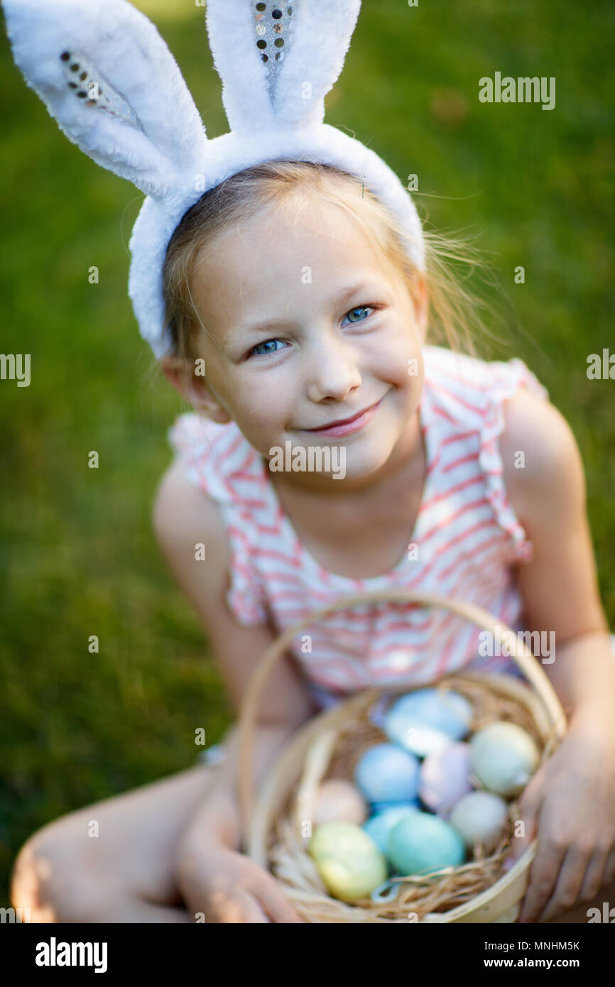 Adorable little girl wearing bunny ears holding a basket with Easter ...