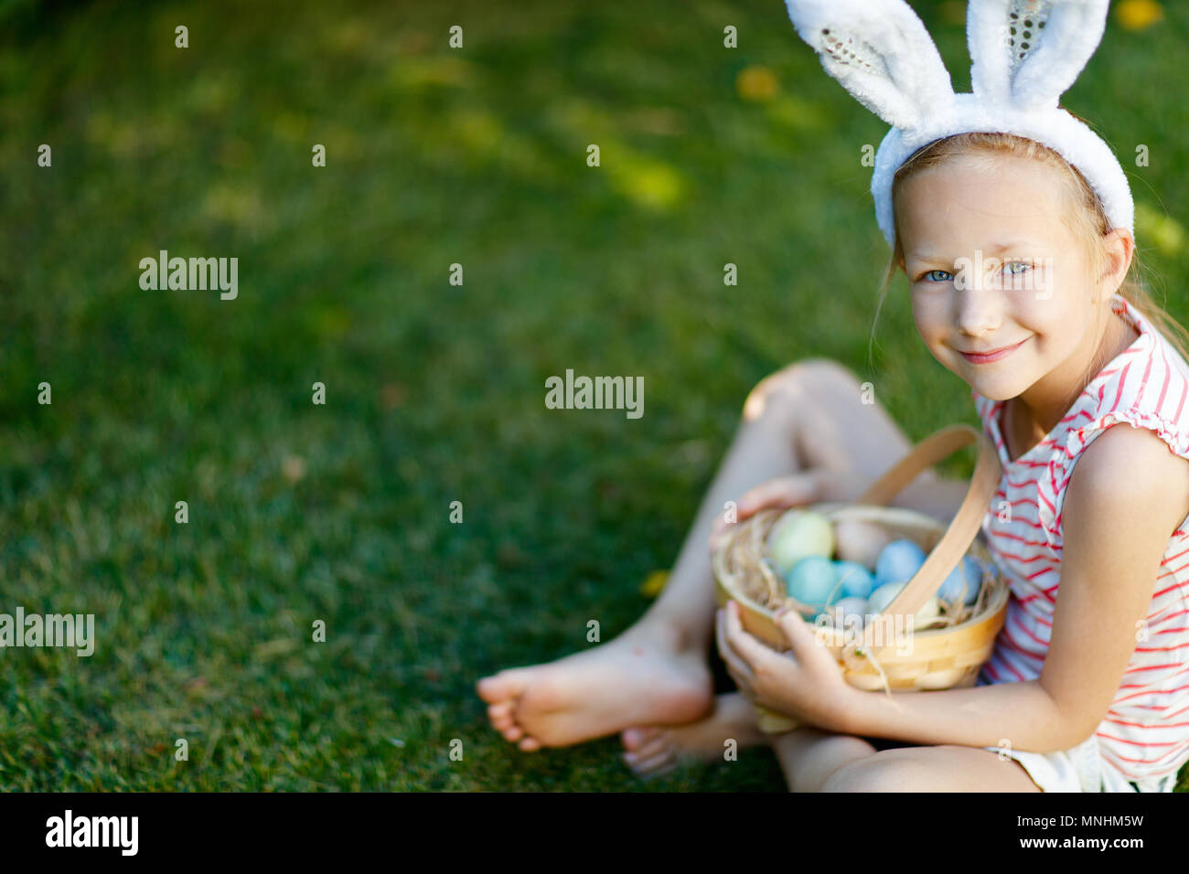 Adorable little girl wearing bunny ears holding a basket with Easter ...