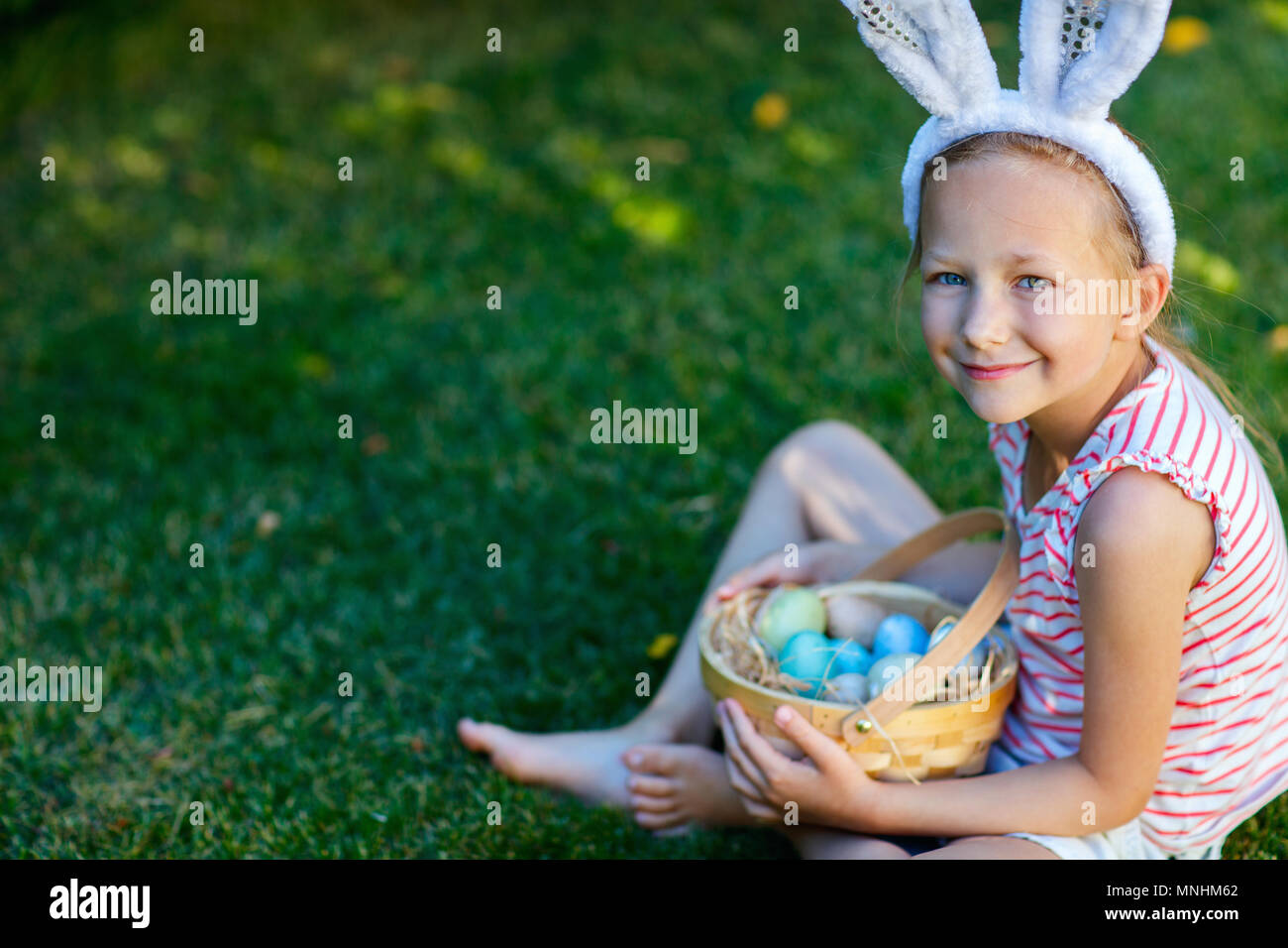 Adorable little girl wearing bunny ears holding a basket with Easter ...