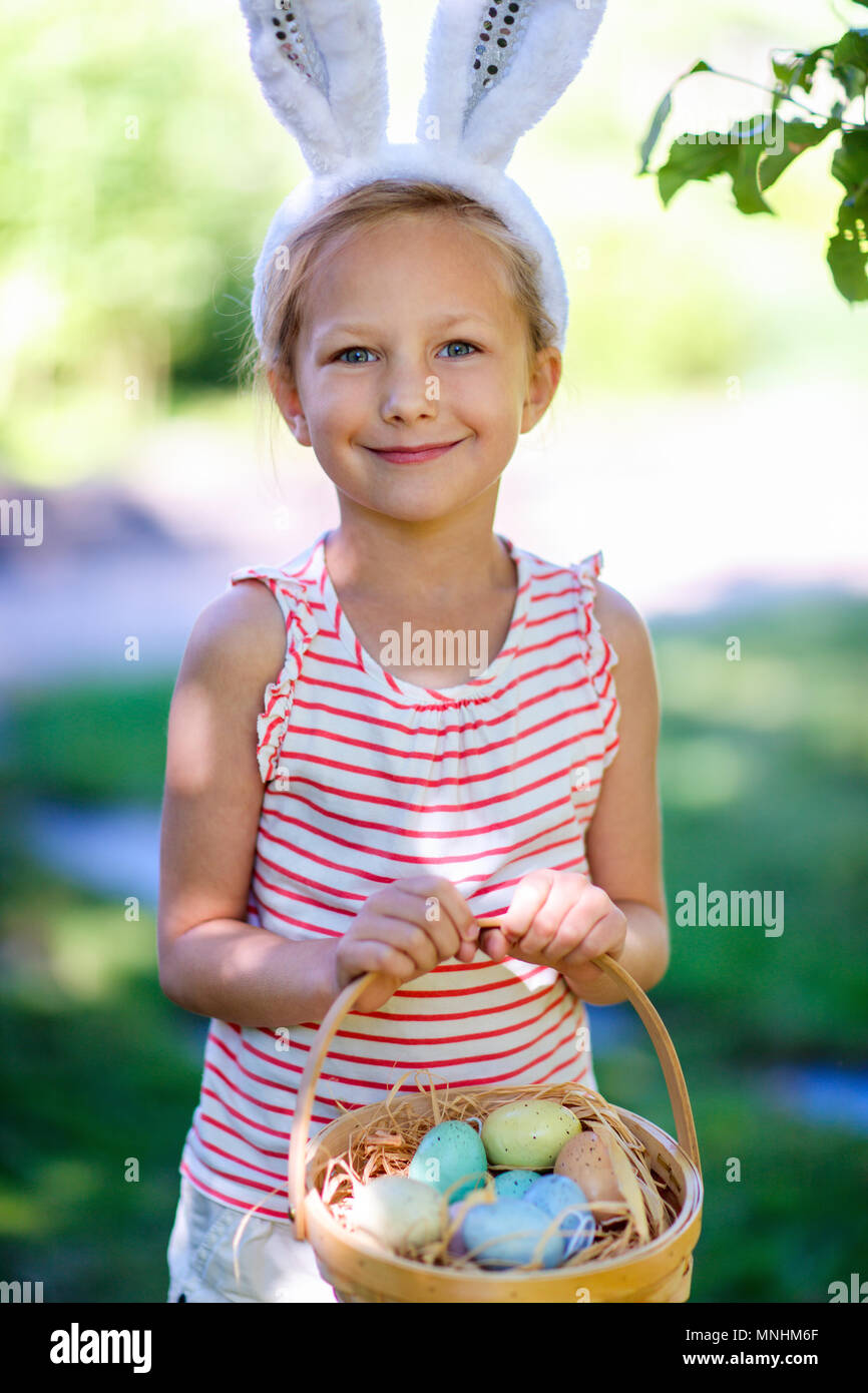 Adorable little girl wearing bunny ears holding a basket with Easter ...