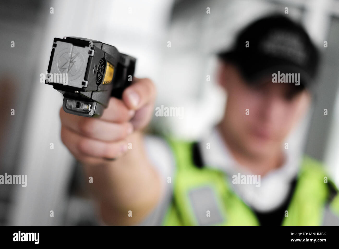 Closeup view of a loaded stun gun in a hand of a young man wearing high visibility vest Stock Photo