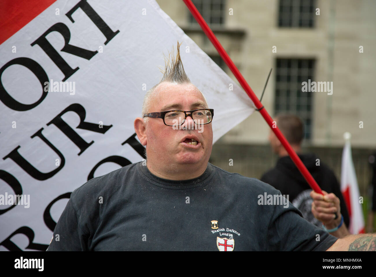 A member of the EDL stands in front of a support our troops banner Stock Photo