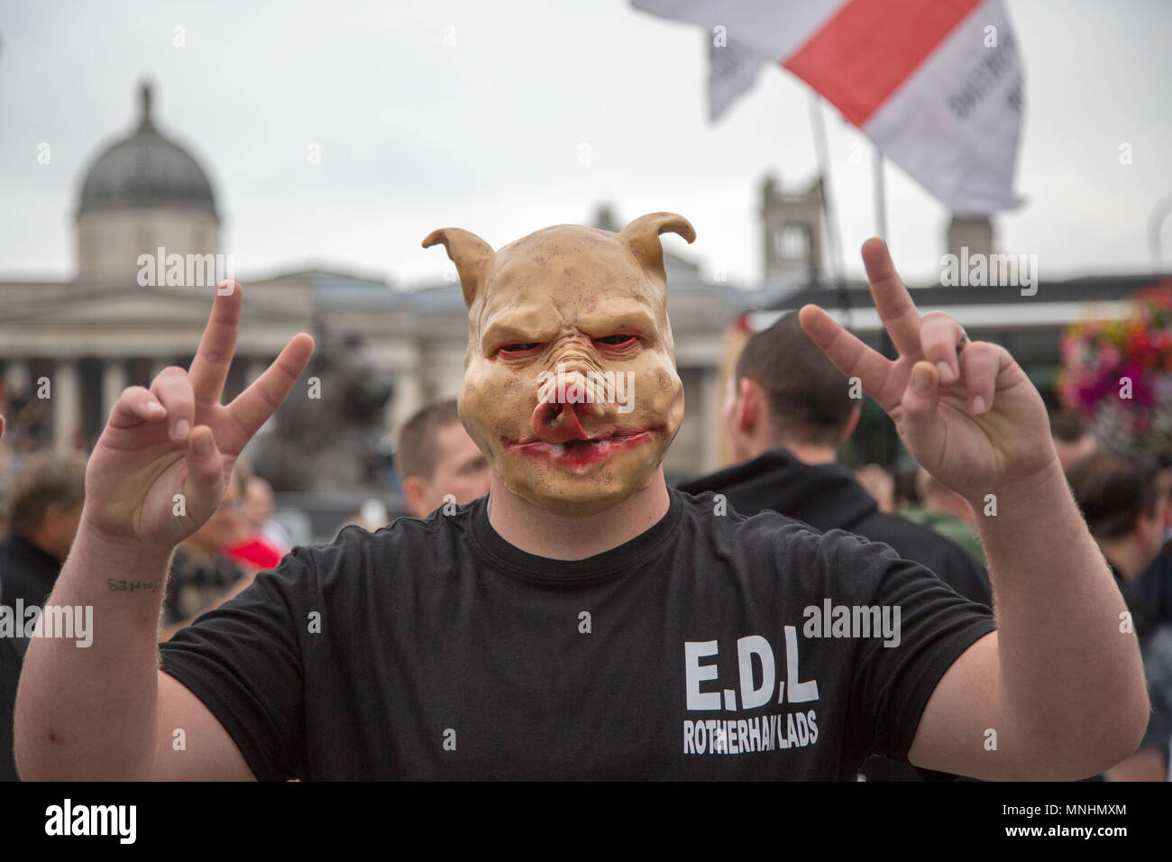 A member of the EDL wearing a pig mask stands in Trafalgar Square, London Stock Photo