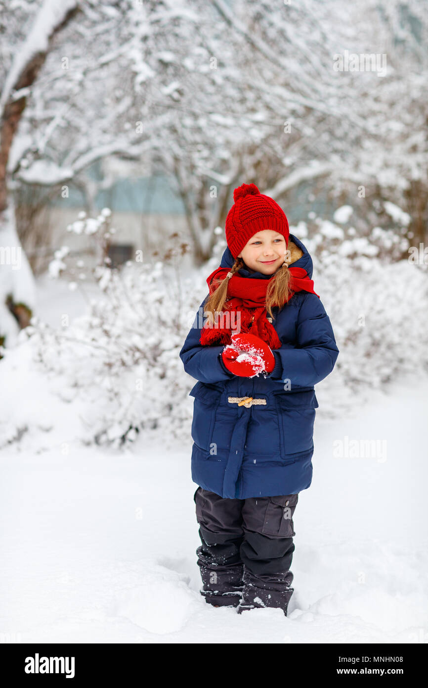 Adorable little girl wearing warm clothes outdoors on beautiful winter snowy day Stock Photo