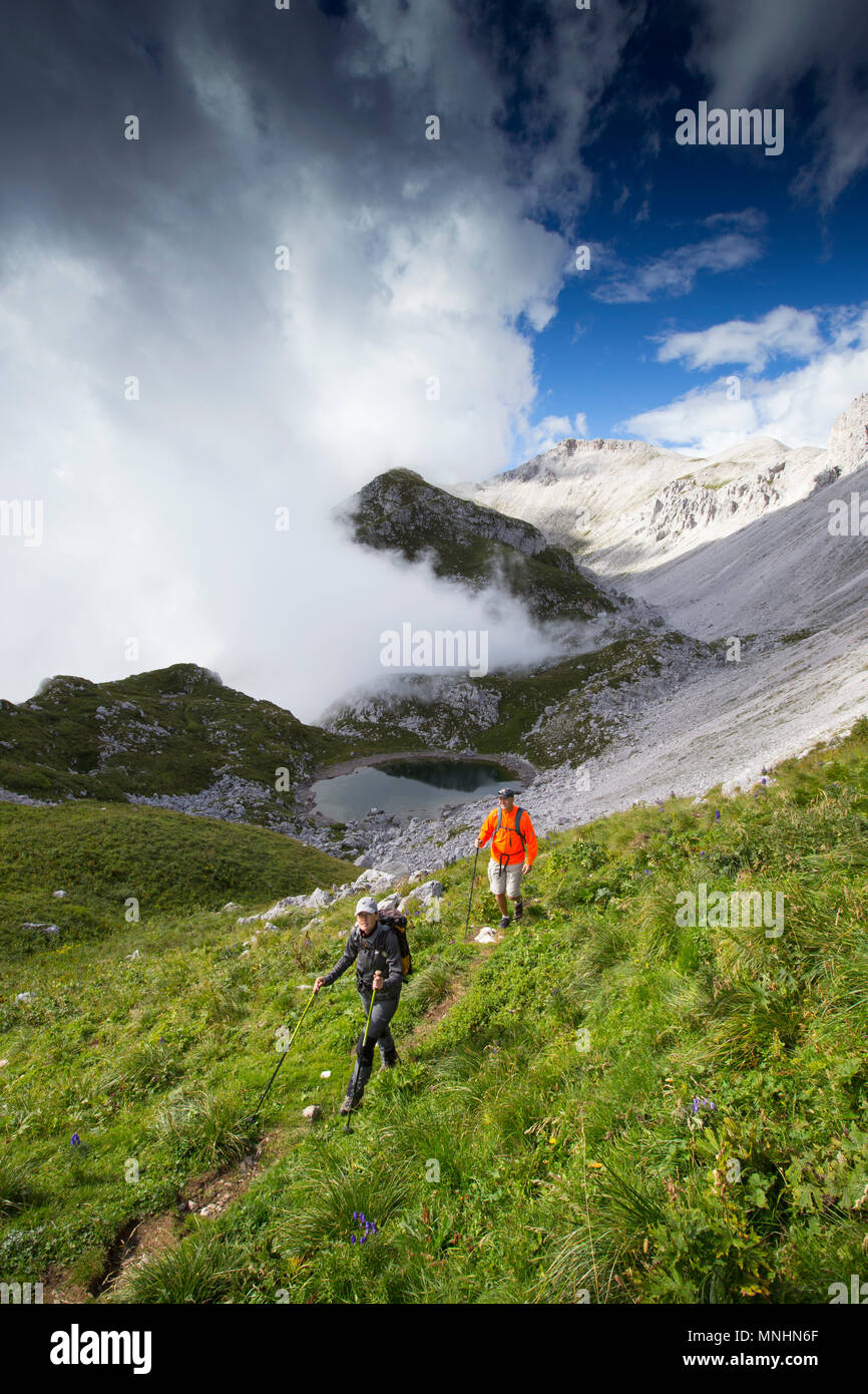 Two hikers near summit of mount Krn with dynamic weather in the background, Julian Alps, Slovenia Stock Photo