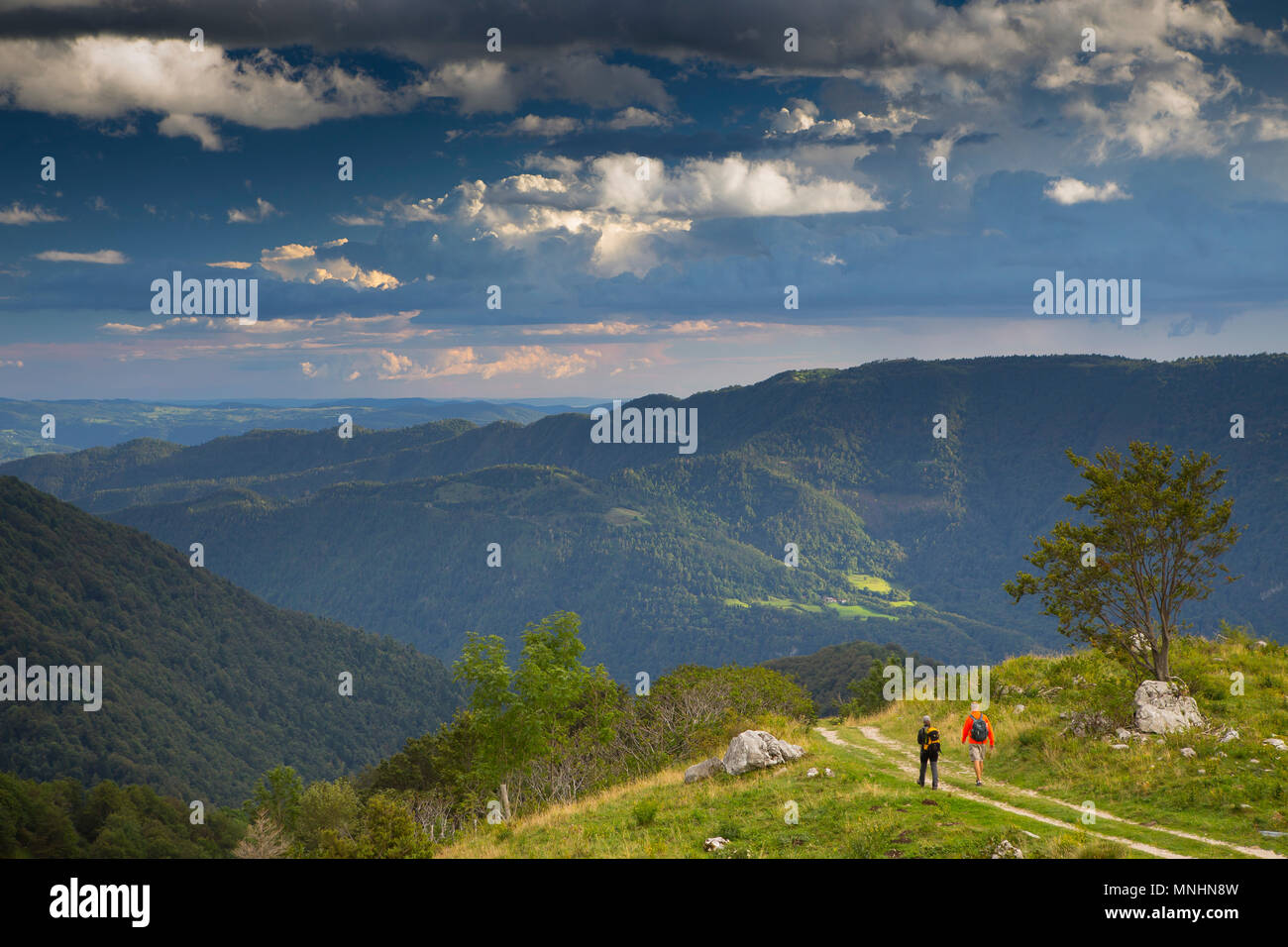 Two hikers walking down Krn mountain at end of the day overlooking beautiful scenery, Krn mountain, Triglav, Slovenia Stock Photo