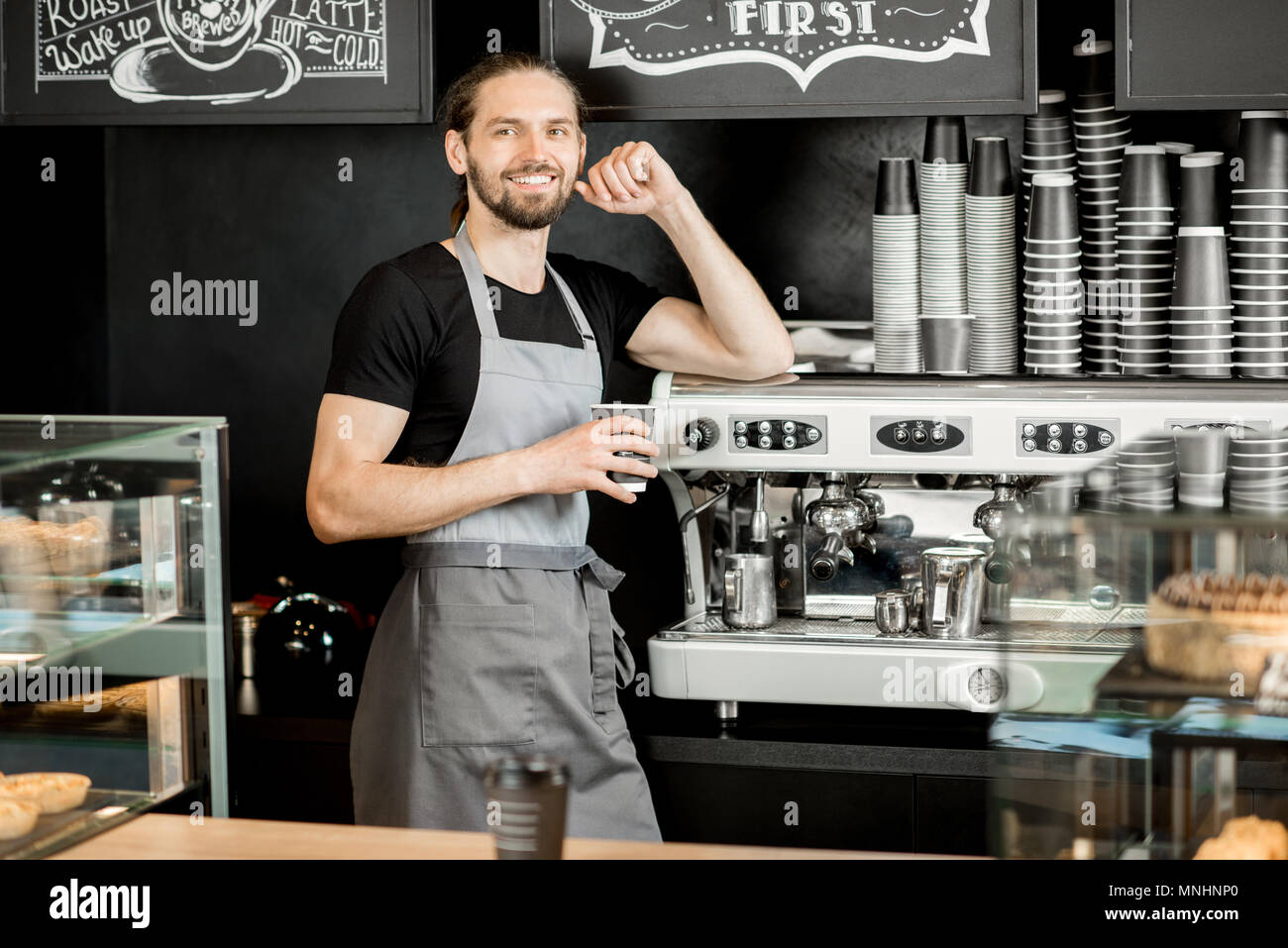 Portrait of a handsome barista in uniform standing near the coffee machine in the coffee shop Stock Photo Alamy