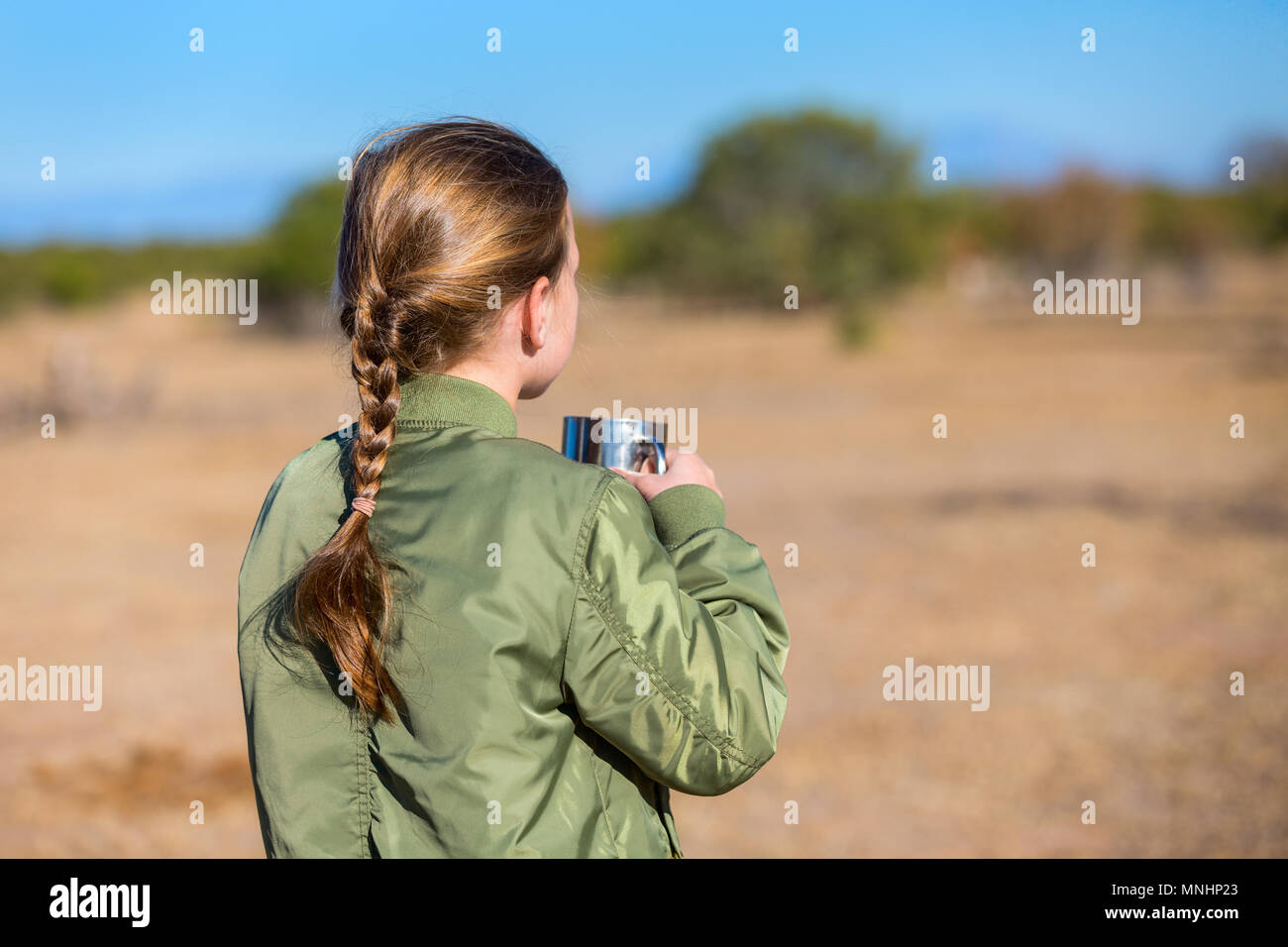 Adorable little girl in South Africa safari with cup of hot chocolate looking at zebras on a distance Stock Photo