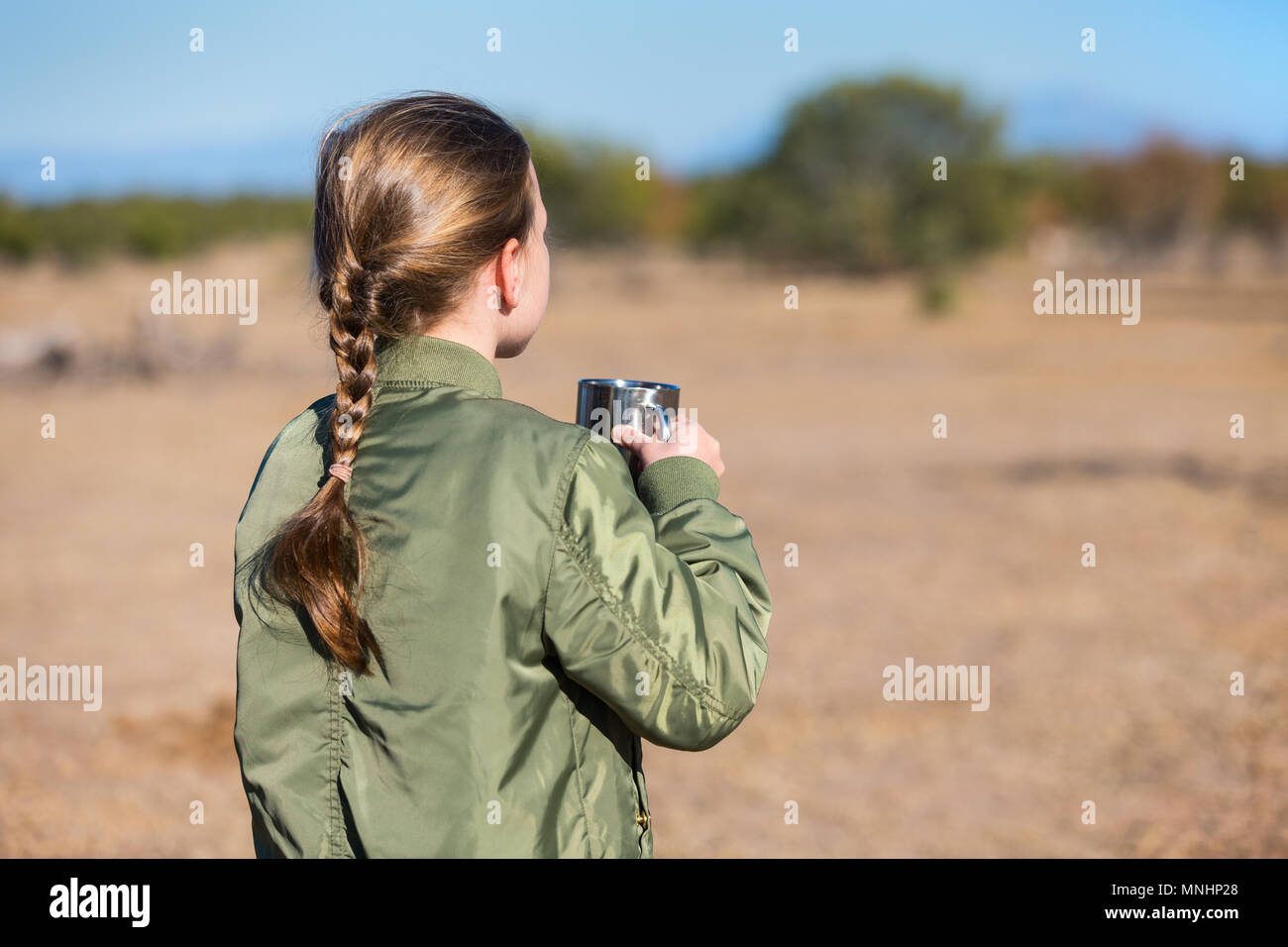 Adorable little girl in South Africa safari with cup of hot chocolate looking at zebras on a distance Stock Photo