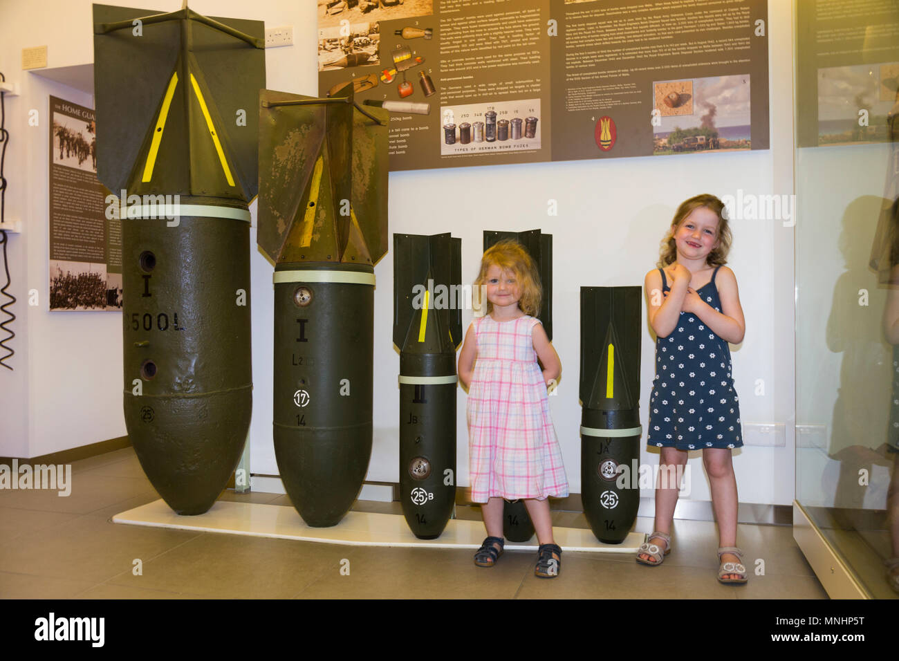 Display of bombs of various sizes used by axis countries Germany & Italy against Malta during World War II. Accompanied by young children child kid kids at the Malta at War Museum in Malta Stock Photo