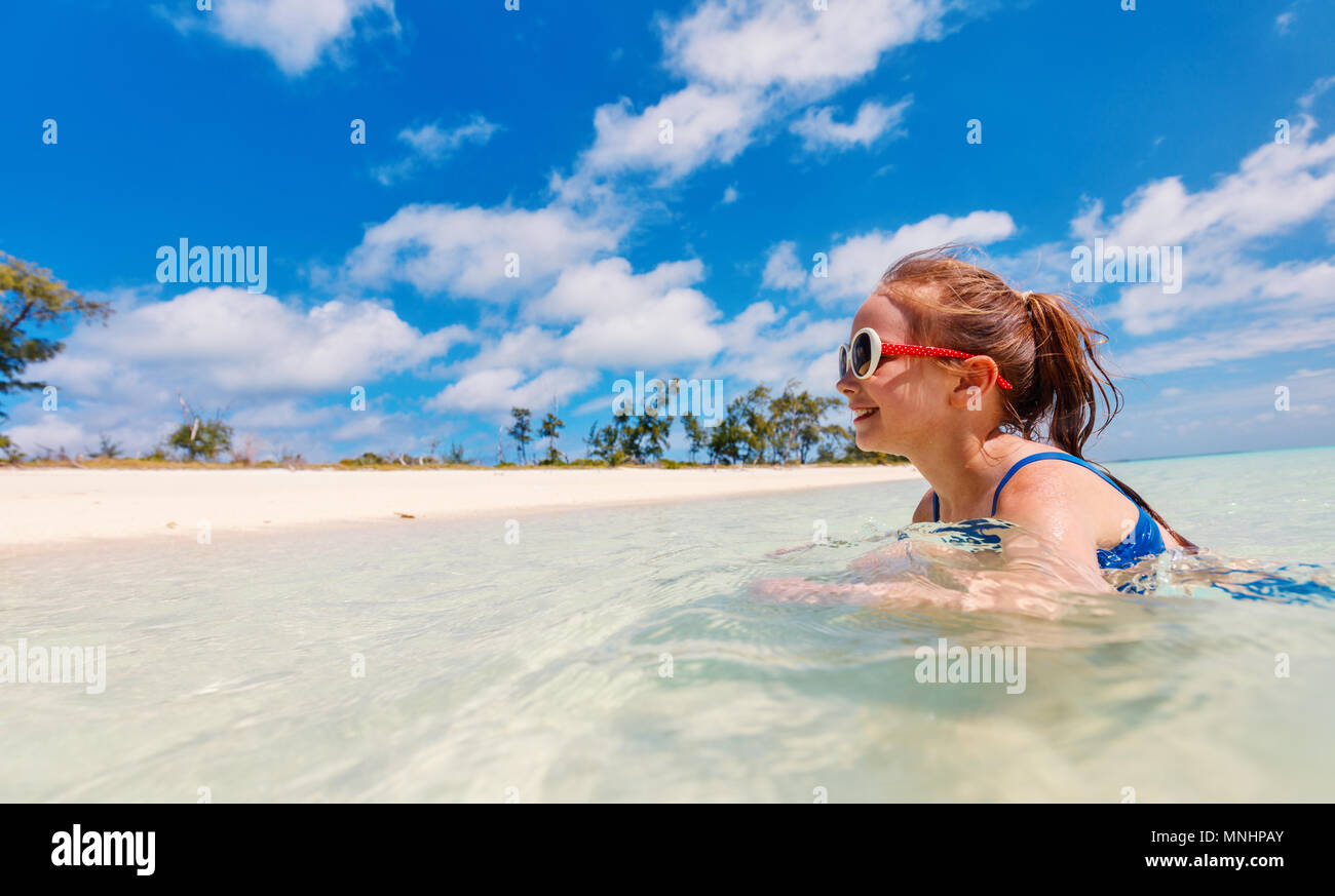 Little girl on vacation swimming in a shallow water at tropical lagoon